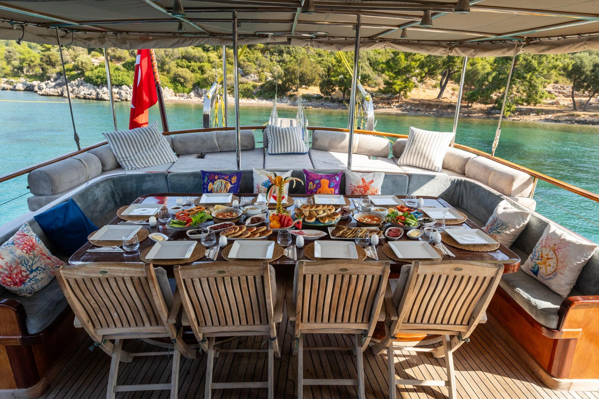 yacht aft deck dining area with breakfast spread including fresh fruits, pastries and table settings