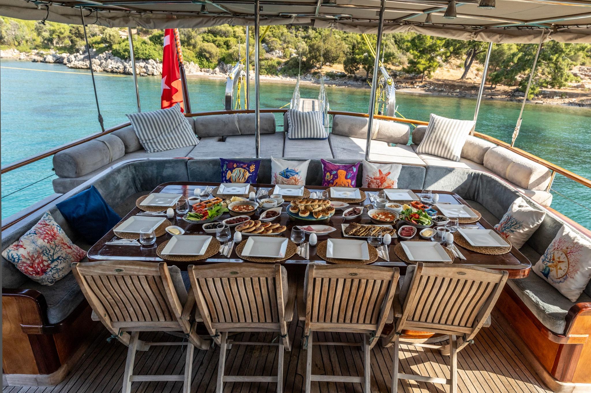 yacht aft deck dining table set with Mediterranean food spread and beverages