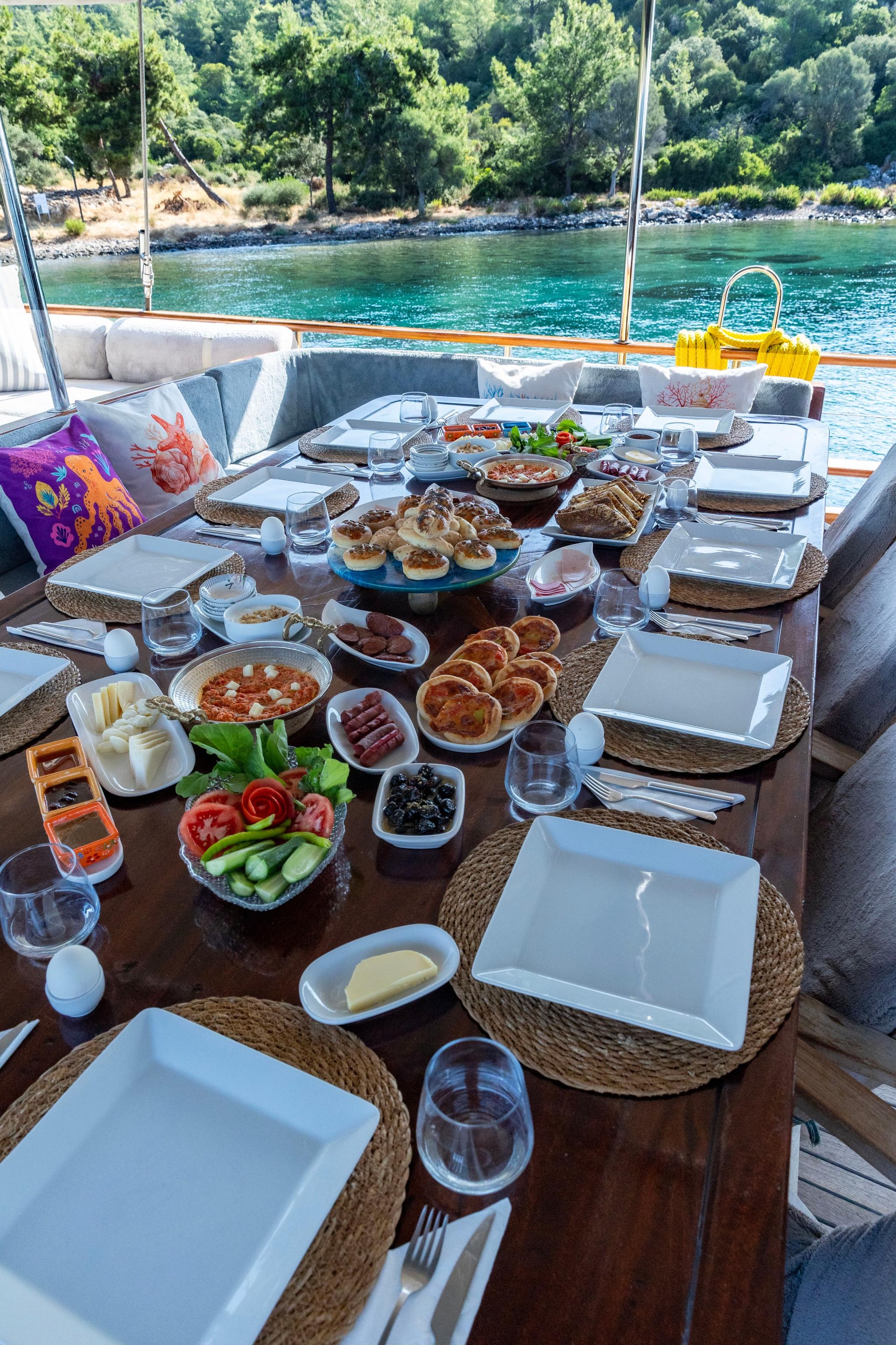 elaborate breakfast spread with pastries, fresh fruit, eggs and beverages on yacht dining table