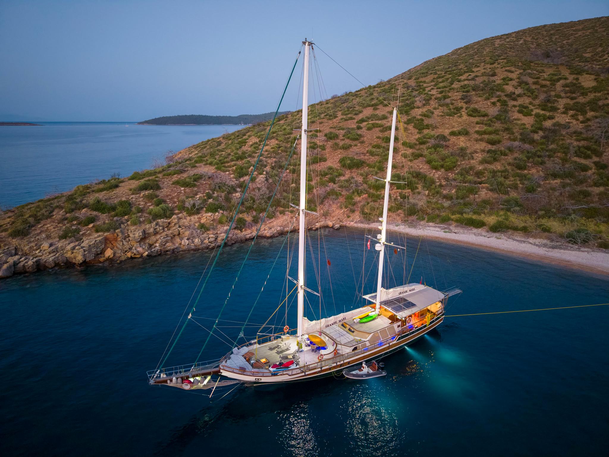 aerial view of traditional wooden gulet yacht anchored in crystal clear turquoise waters near Mediterranean coastline