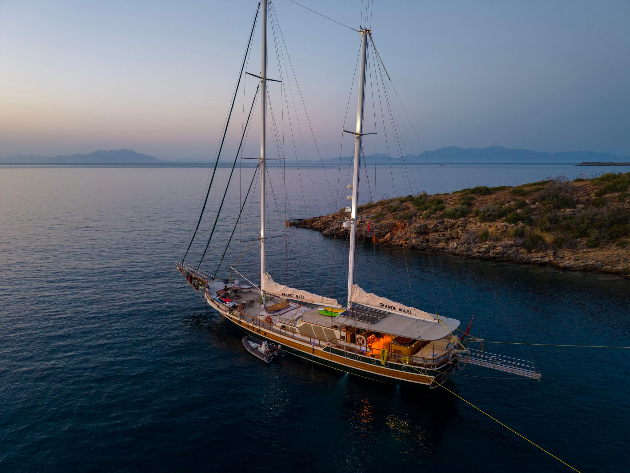 aerial view of traditional wooden gulet Grande Mare anchored in crystal clear Mediterranean bay at golden hour