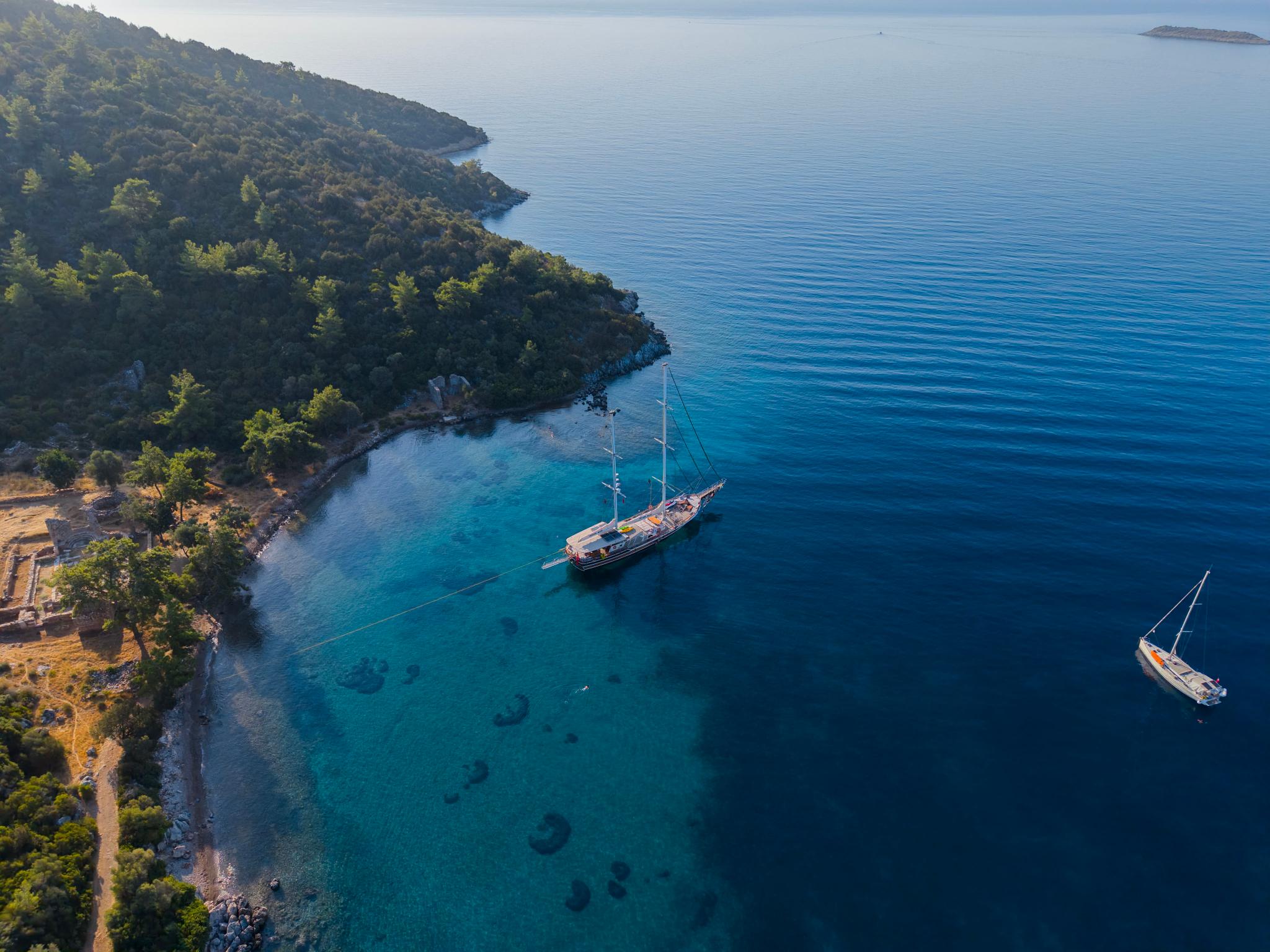 aerial view of traditional wooden gulet anchored in crystal clear turquoise bay