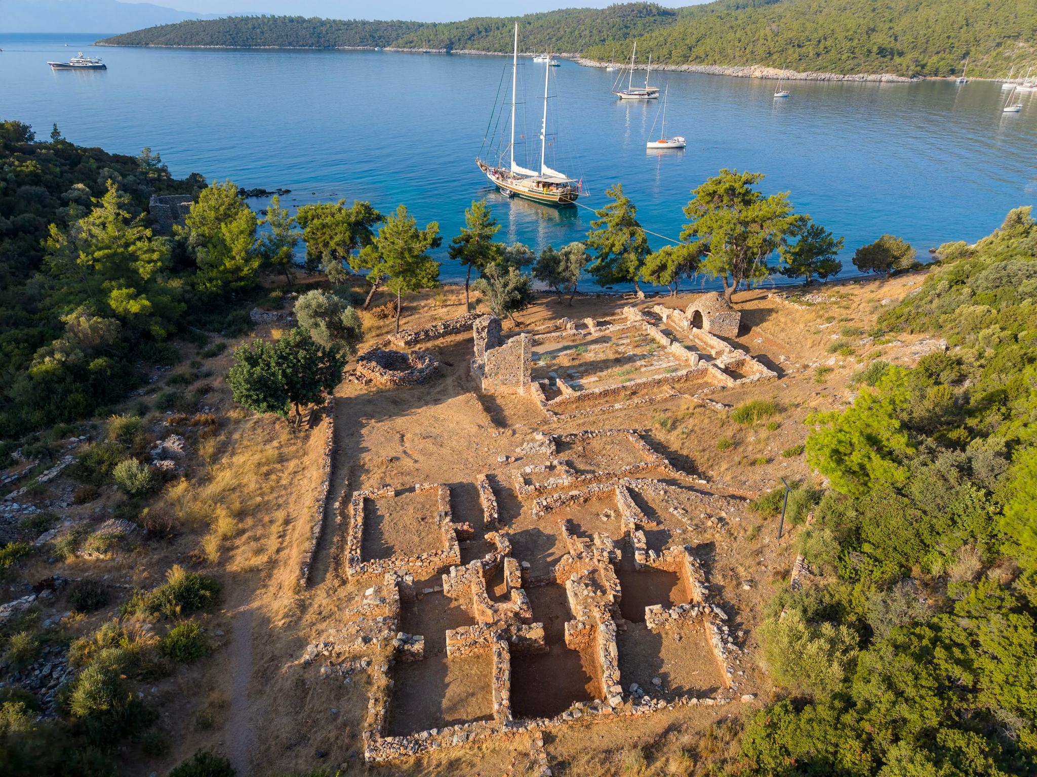 aerial view of traditional gulet yacht anchored in Mediterranean bay near ancient stone ruins