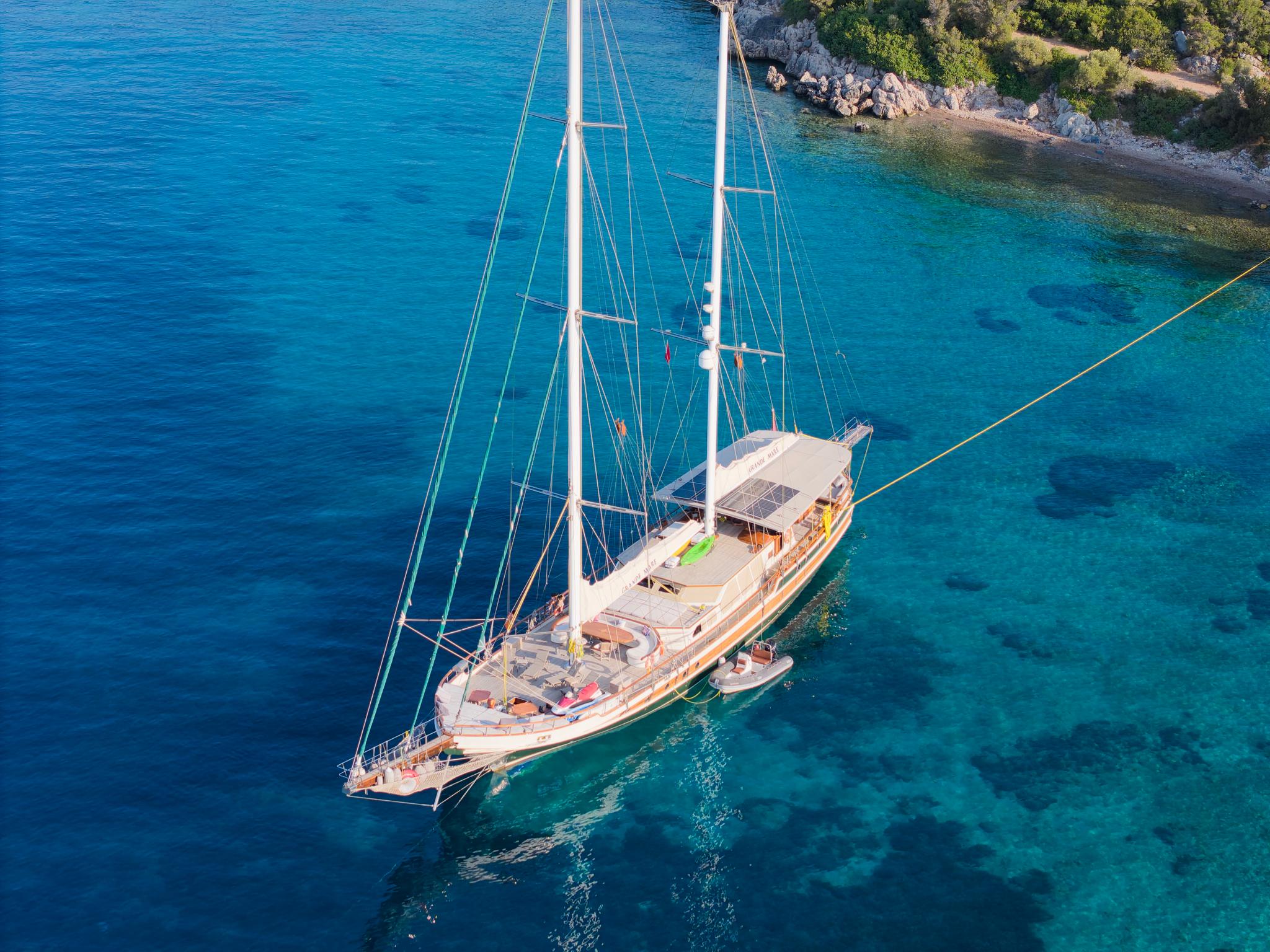 aerial view of traditional wooden gulet yacht at anchor in crystal clear turquoise bay