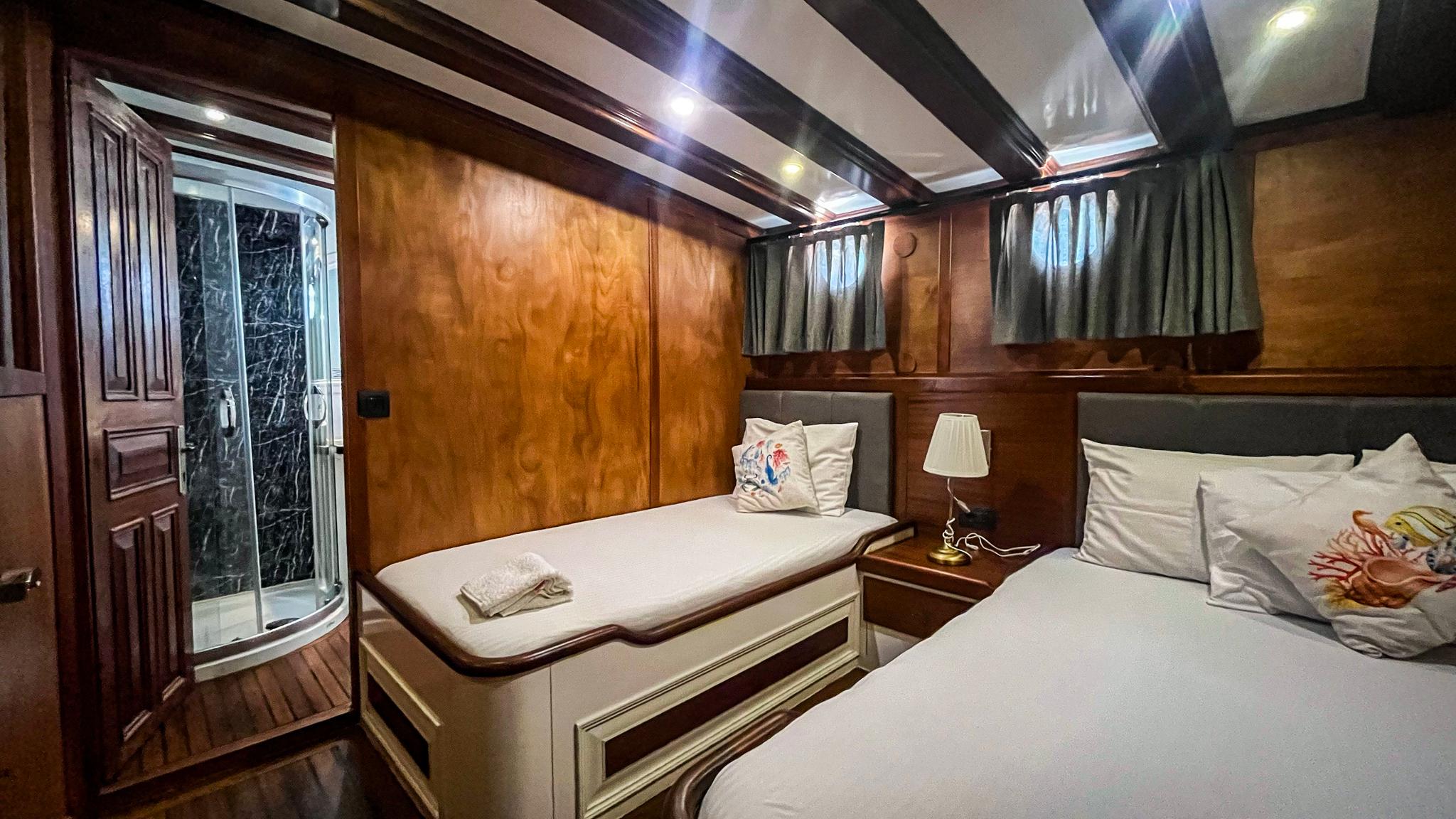 yacht twin cabin with two single beds, wood paneling and marble bathroom door