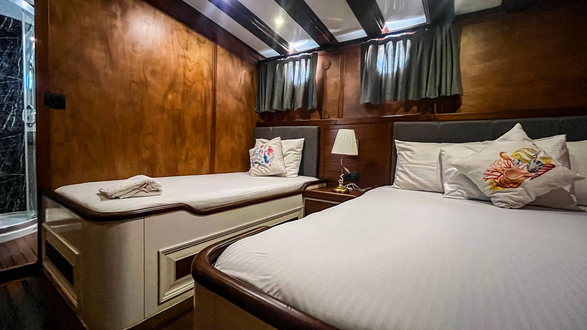yacht guest cabin featuring two single beds with white linens and decorative pillows