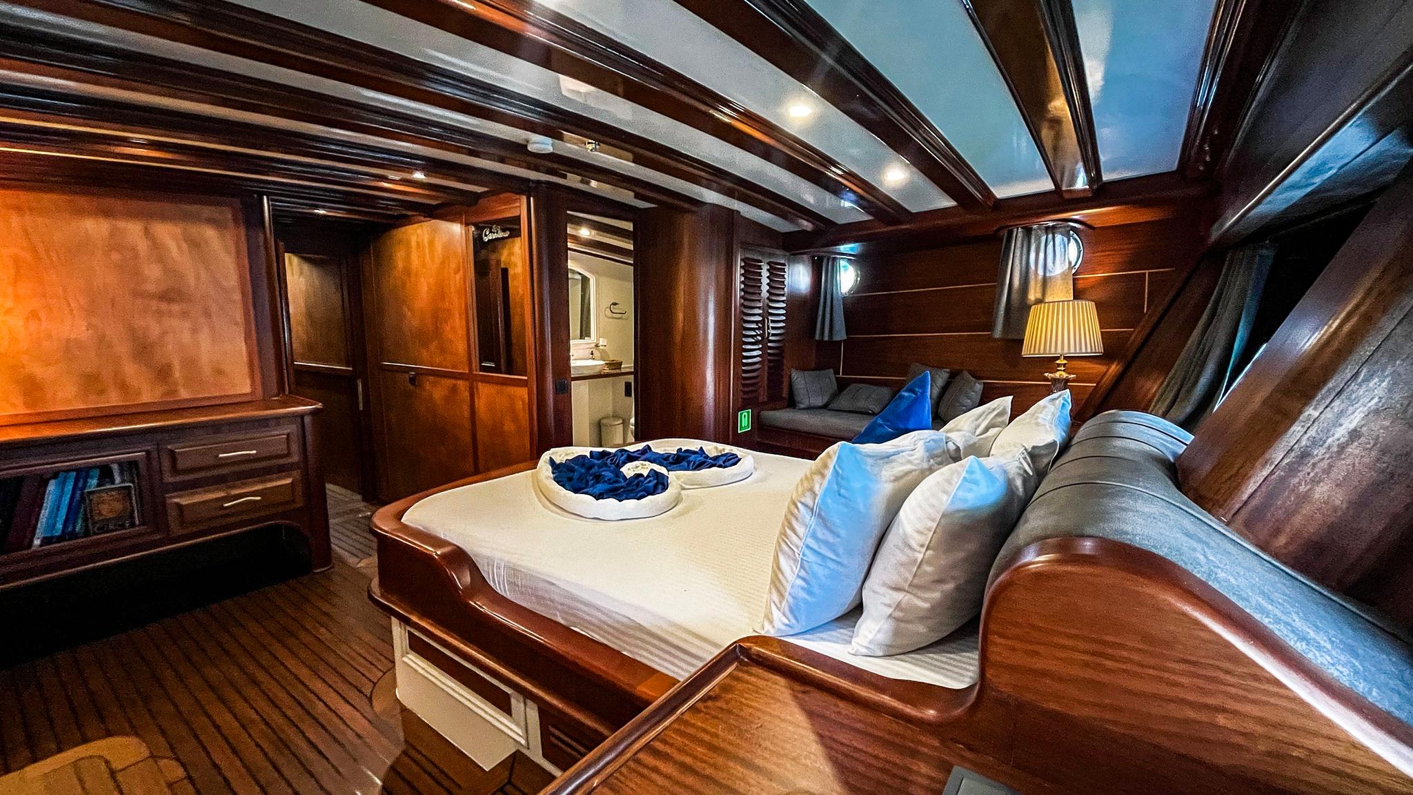 luxurious master cabin featuring king bed with white linens and en-suite bathroom entrance