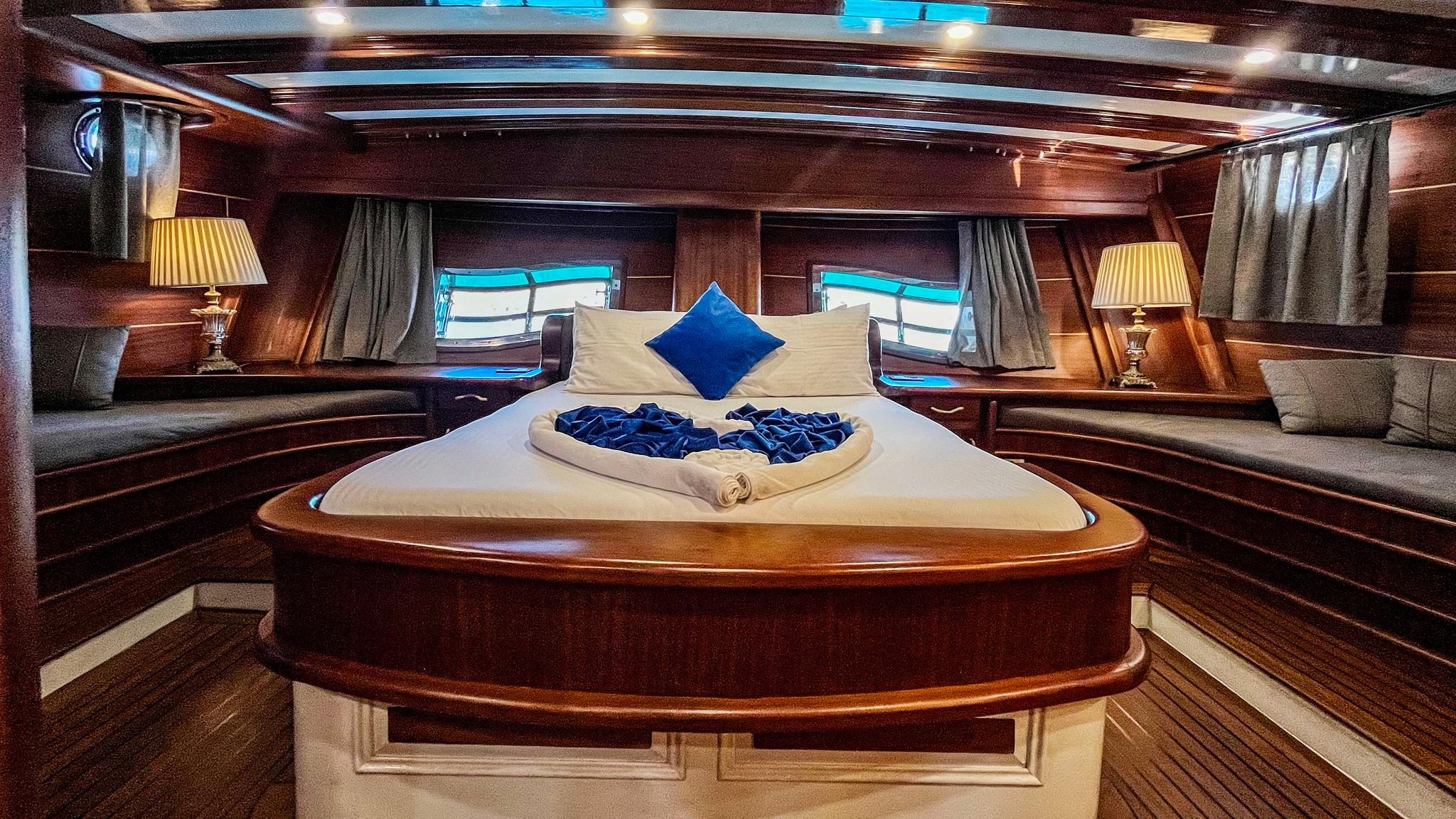Luxury yacht master cabin featuring king bed with blue pillows and towel arrangement