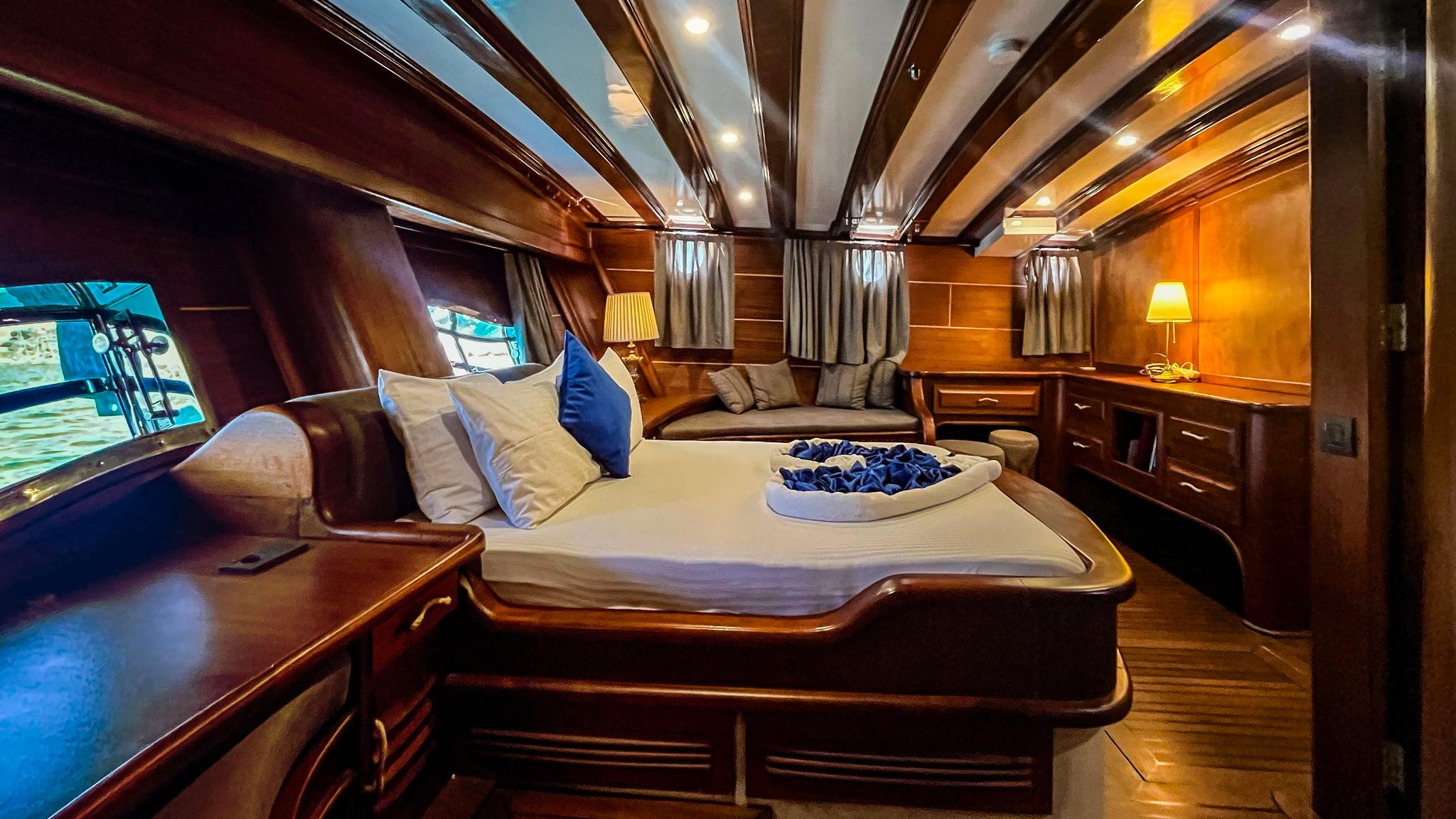 luxurious master cabin featuring king bed with white linens, built-in seating area, and panoramic windows