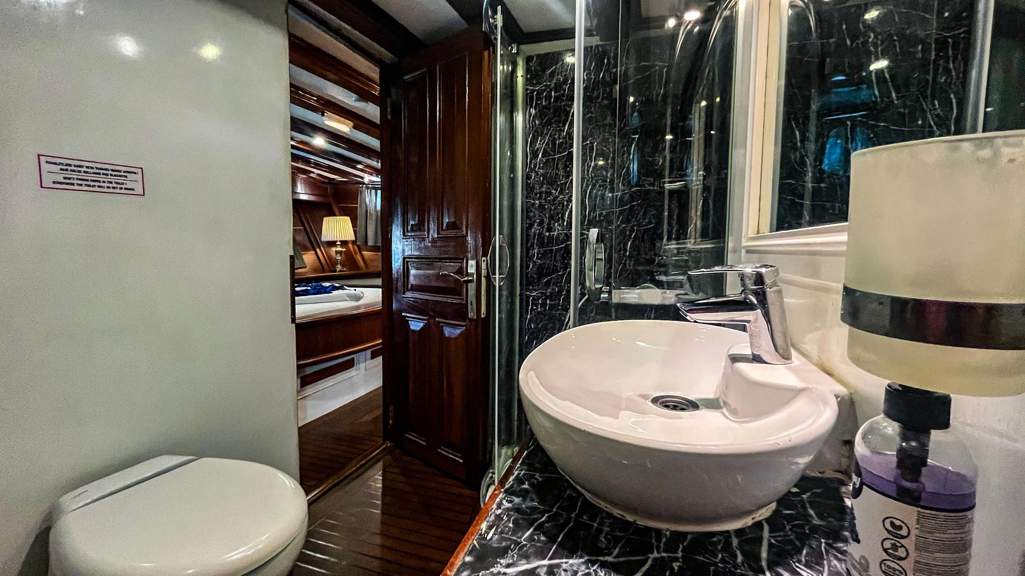 luxury yacht bathroom featuring black marble shower enclosure and white vessel basin