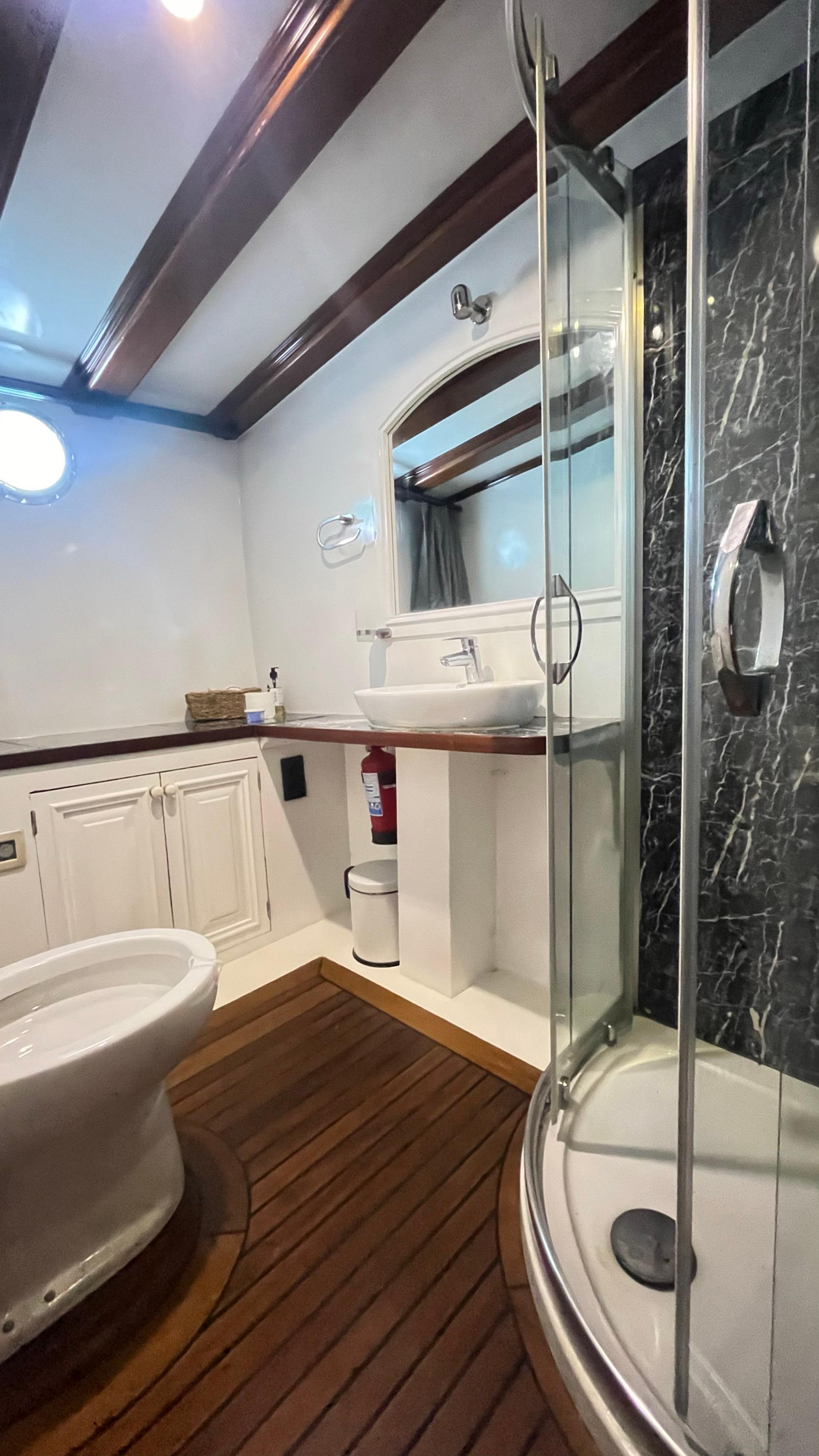 yacht bathroom featuring glass shower enclosure, white bathtub and marble vanity with vessel sink