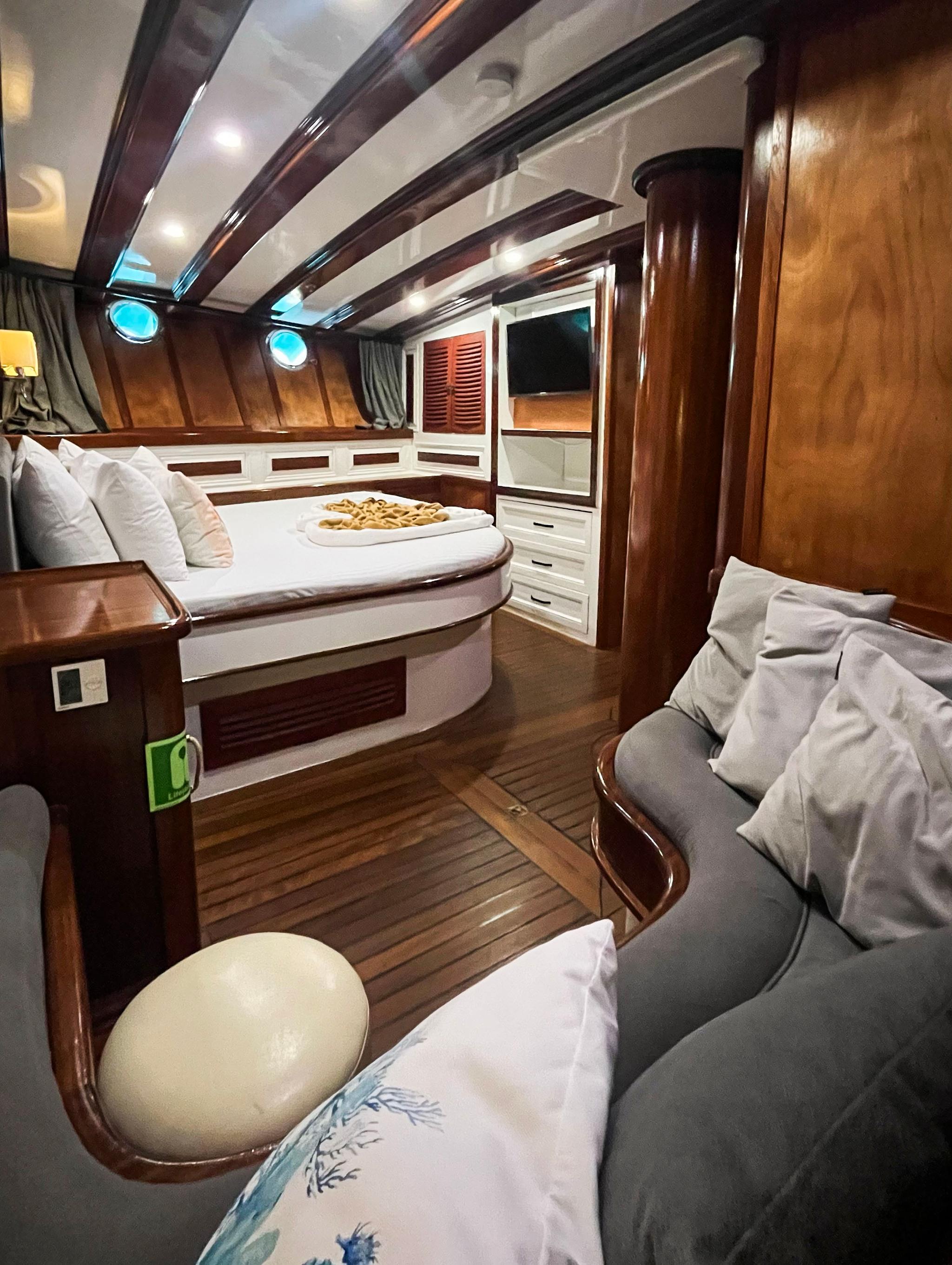 yacht cabin with curved bed, built-in storage, portholes and upholstered seating