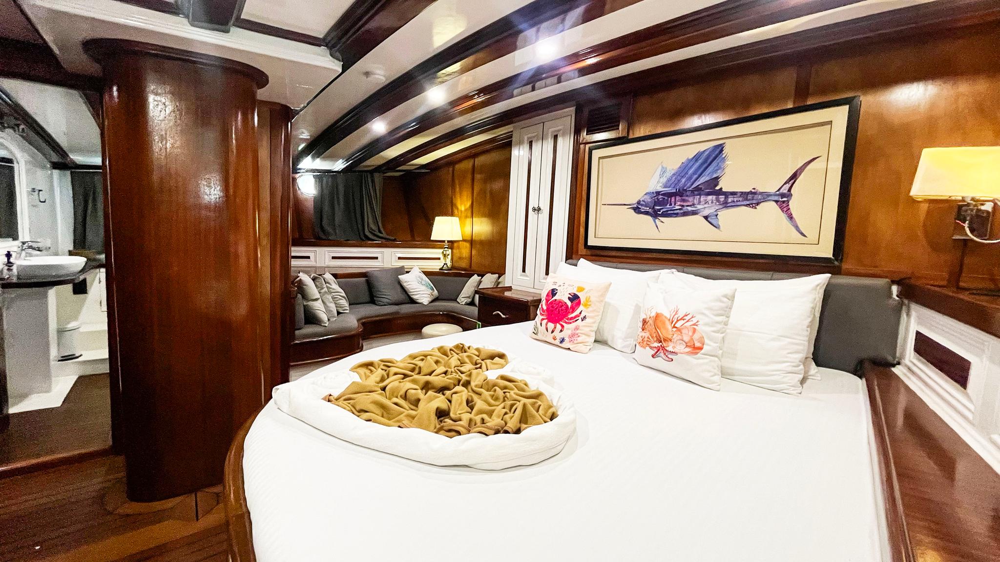 yacht cabin interior with white bedding, nautical artwork, and marble en-suite bathroom visible