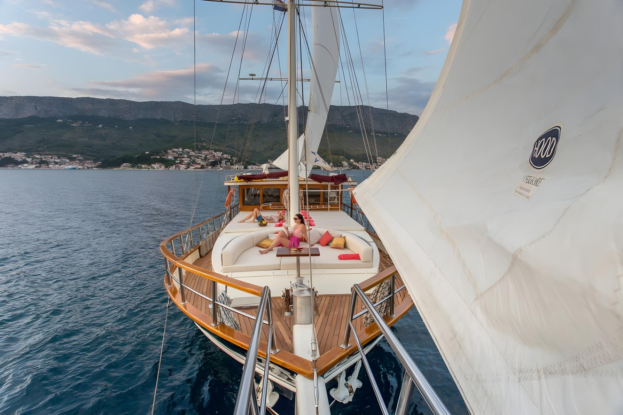 bow deck with curved white seating and guests relaxing on luxury gulet