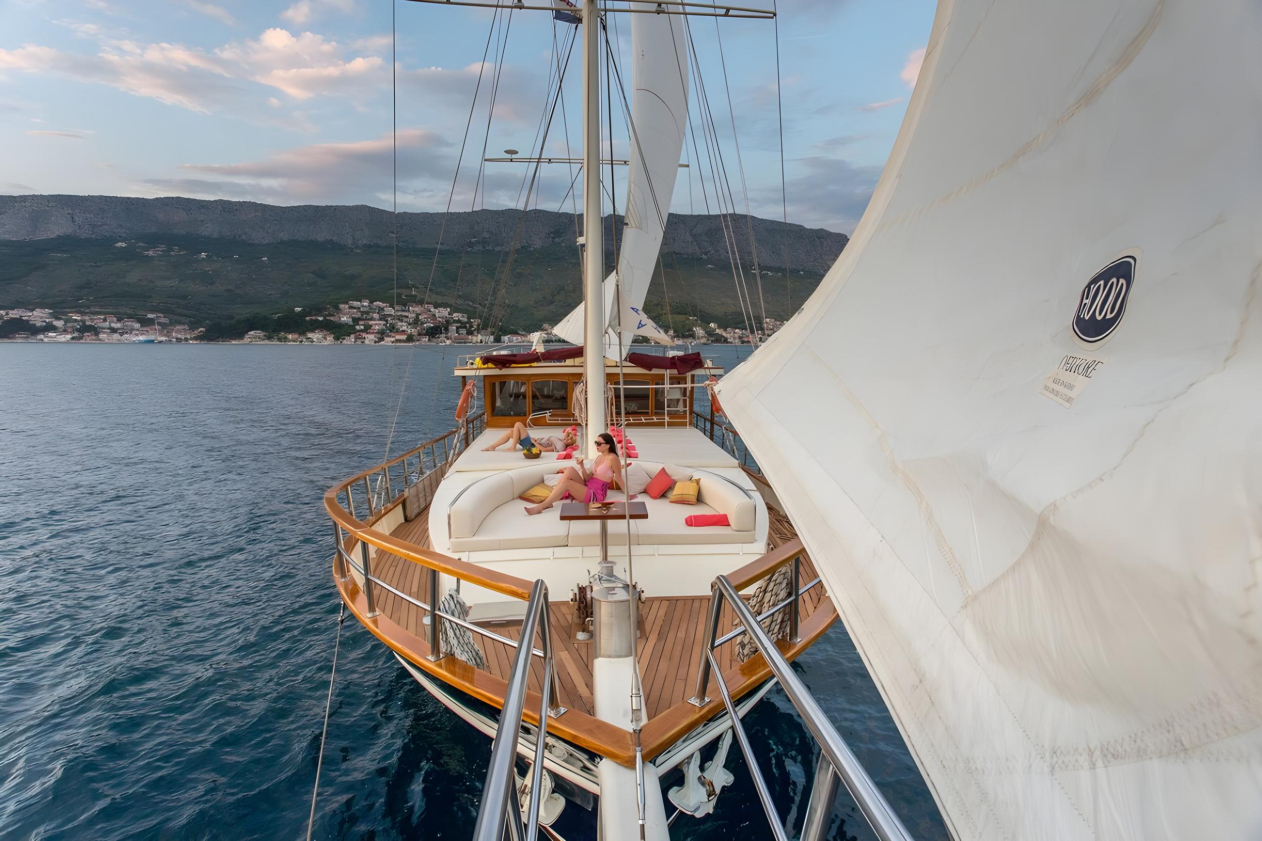 bow deck with curved white seating and guests relaxing on luxury gulet