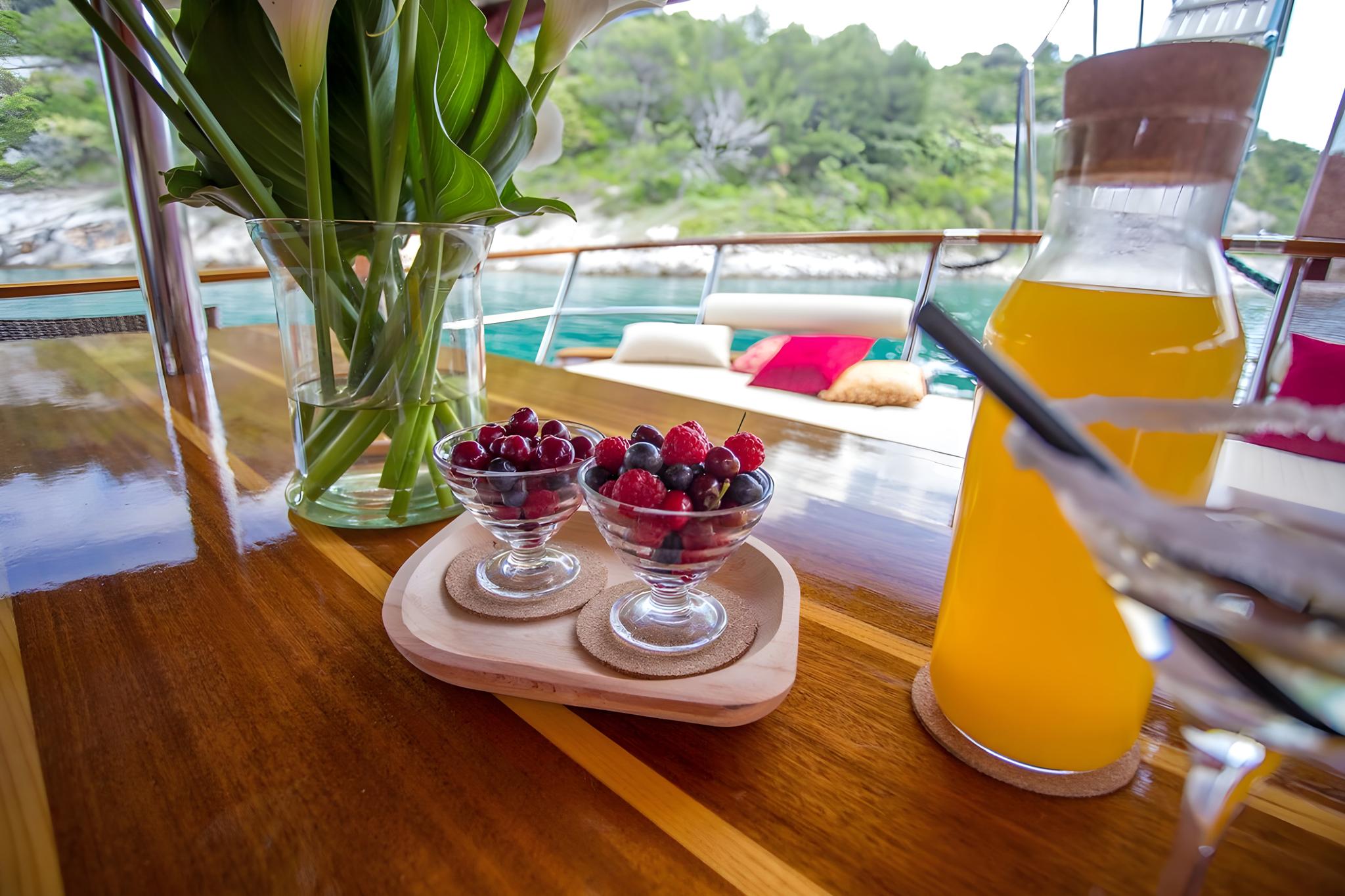 yacht breakfast table with fresh berries in glass bowls and orange juice pitcher