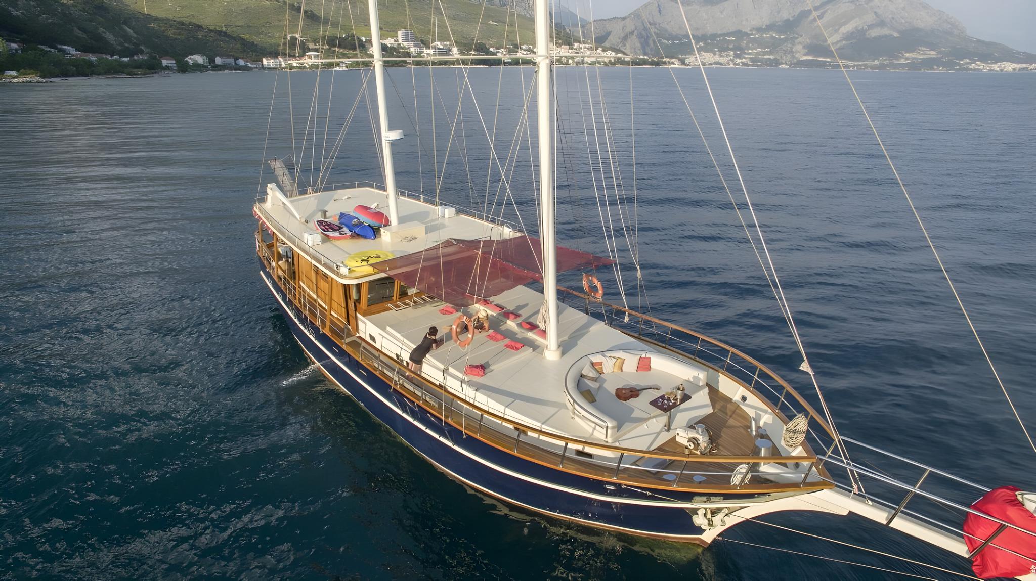 aerial drone shot of traditional wooden gulet with two masts anchored in Mediterranean bay