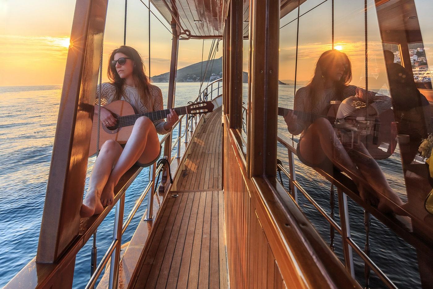 Guests enjoying music on traditional wooden yacht deck at golden hour