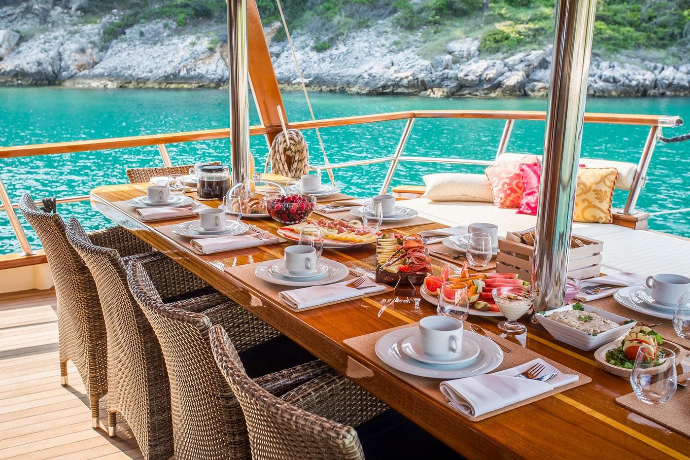 Elegant breakfast table setting on gulet yacht deck with turquoise waters