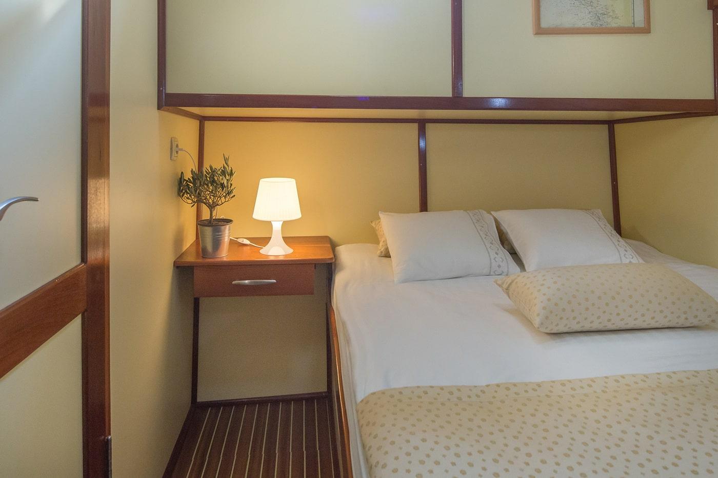 Luxury yacht cabin with white bedding cream headboard wooden floors