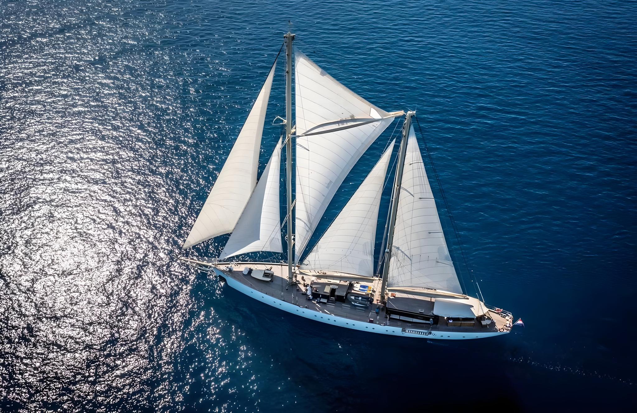 aerial view of traditional sailing gulet with white sails deployed on blue Mediterranean waters
