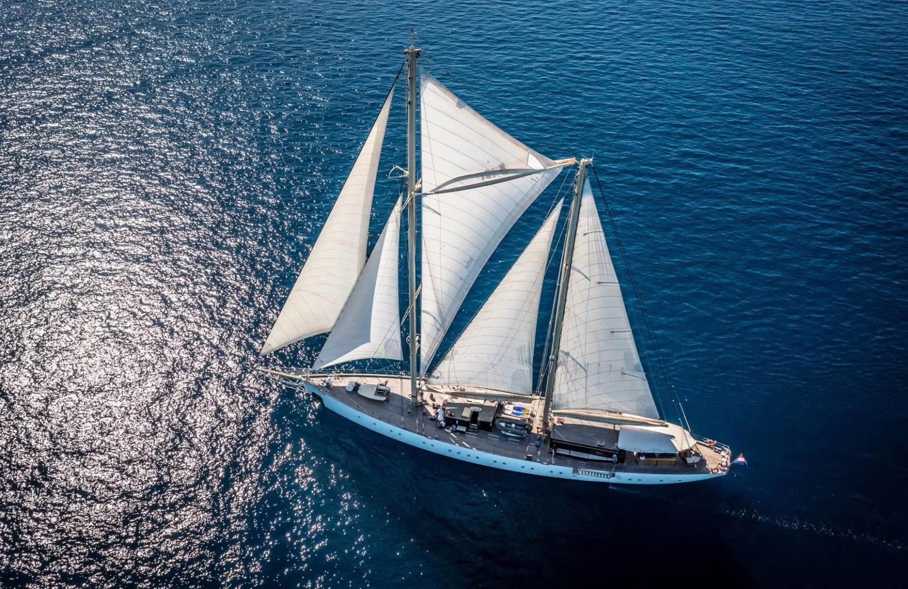 aerial view of traditional sailing gulet with white sails deployed on blue Mediterranean waters