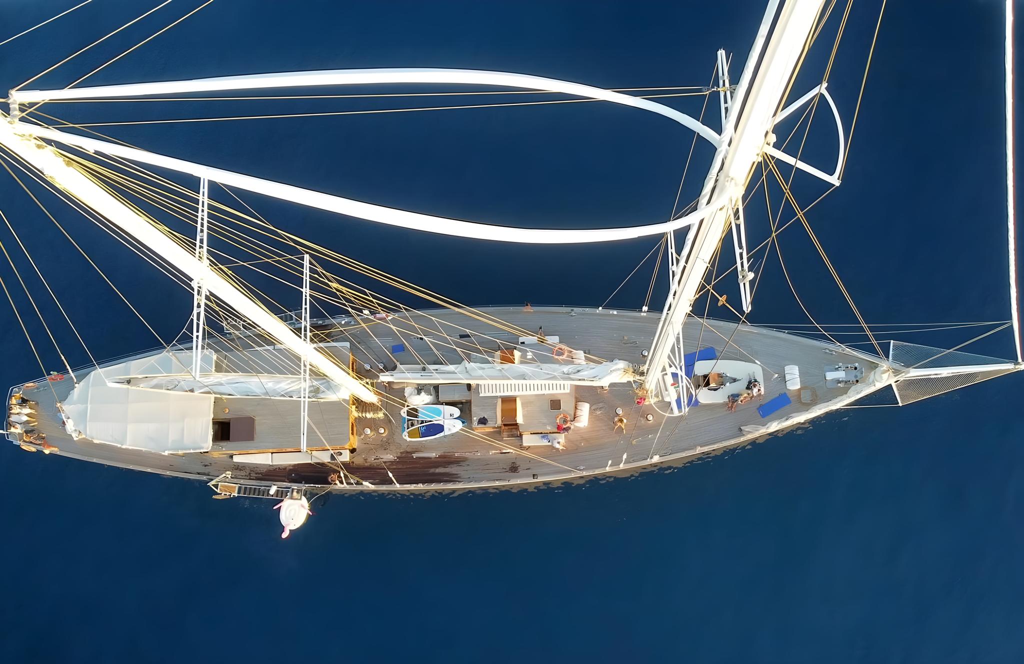 aerial drone shot of traditional sailing yacht with white hull anchored in deep blue waters