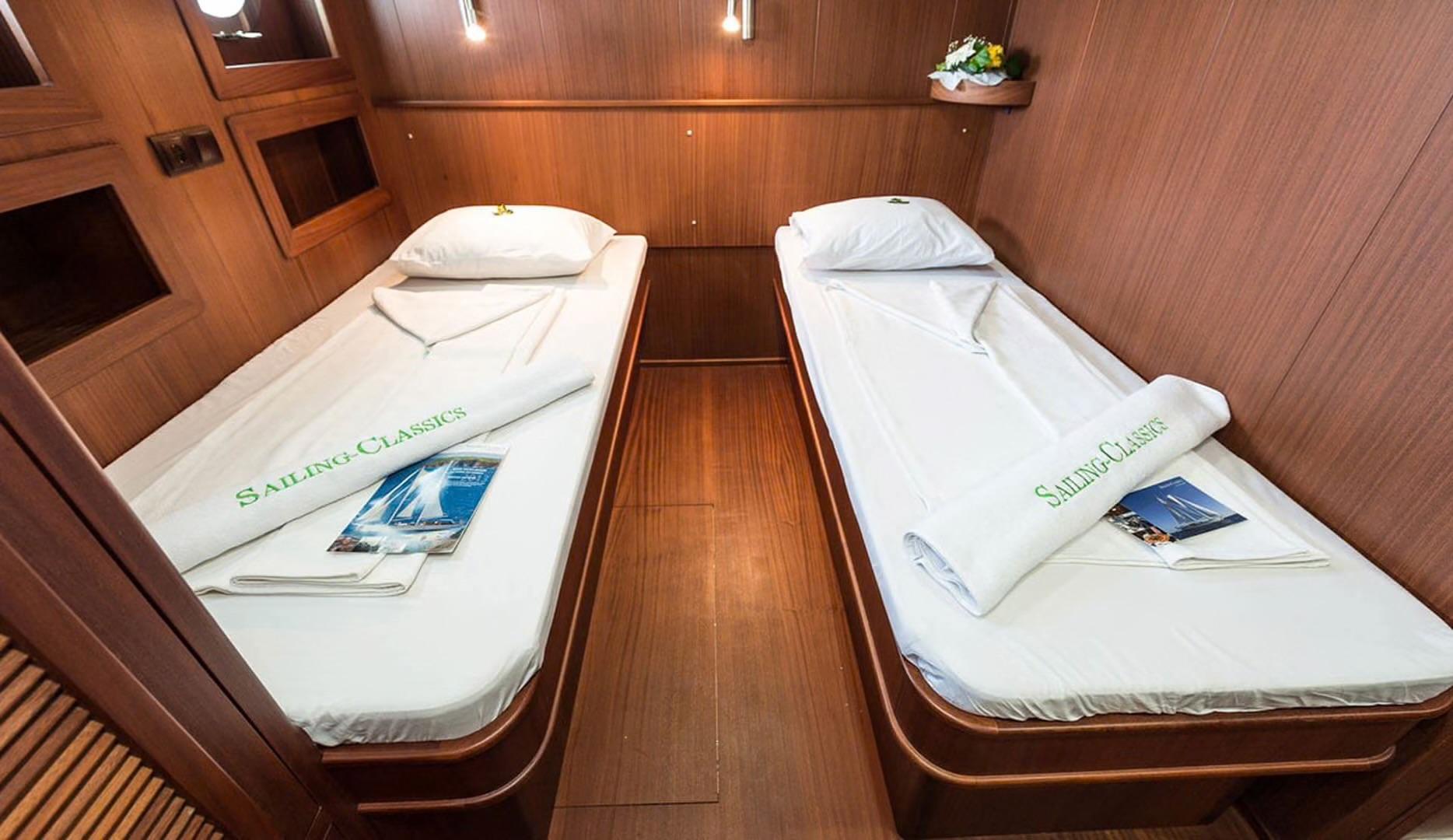 twin guest cabin featuring two single beds with white linens and wooden paneling