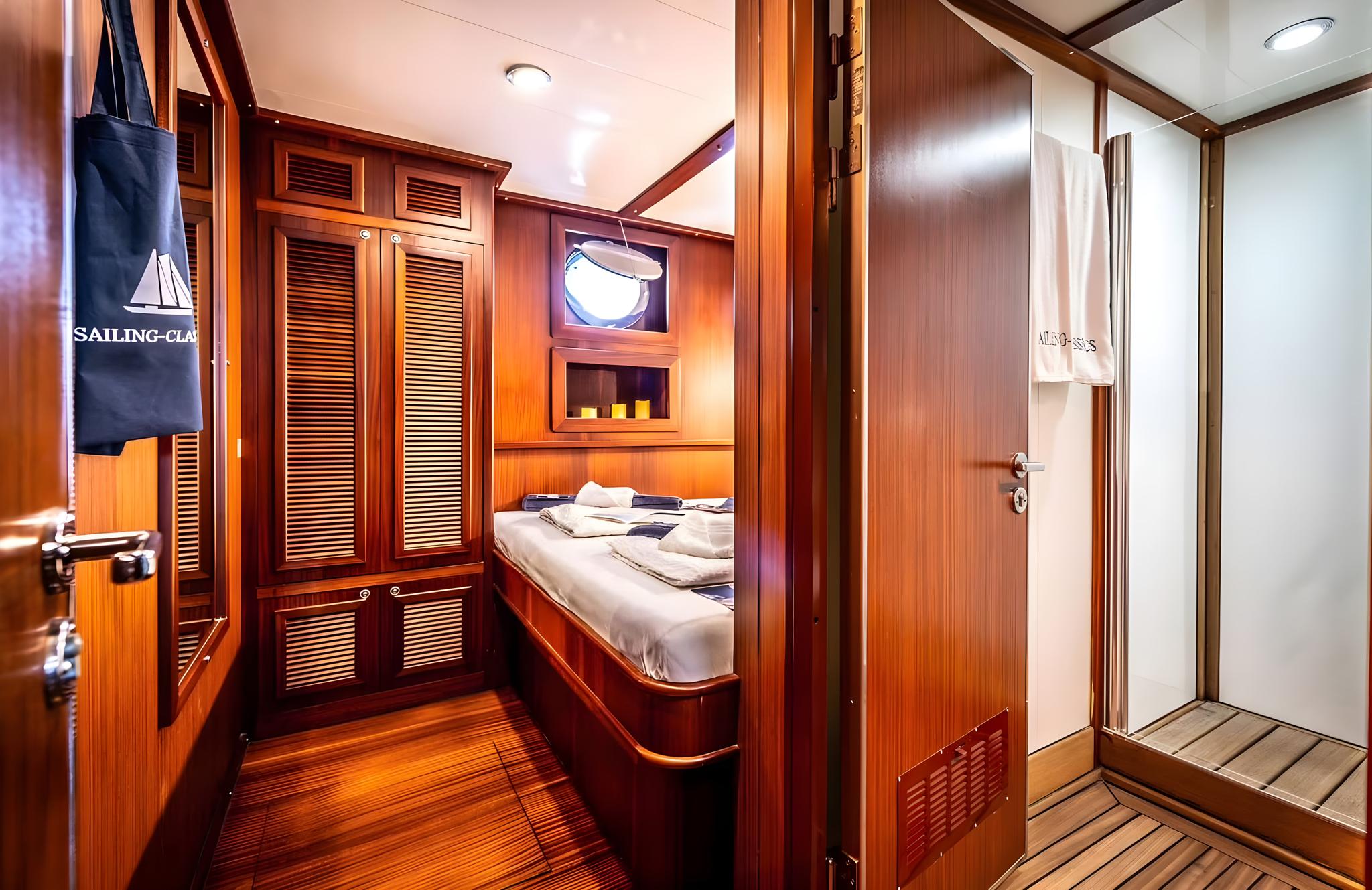 yacht guest cabin with single bed, built-in storage, porthole window, and rich wood paneling
