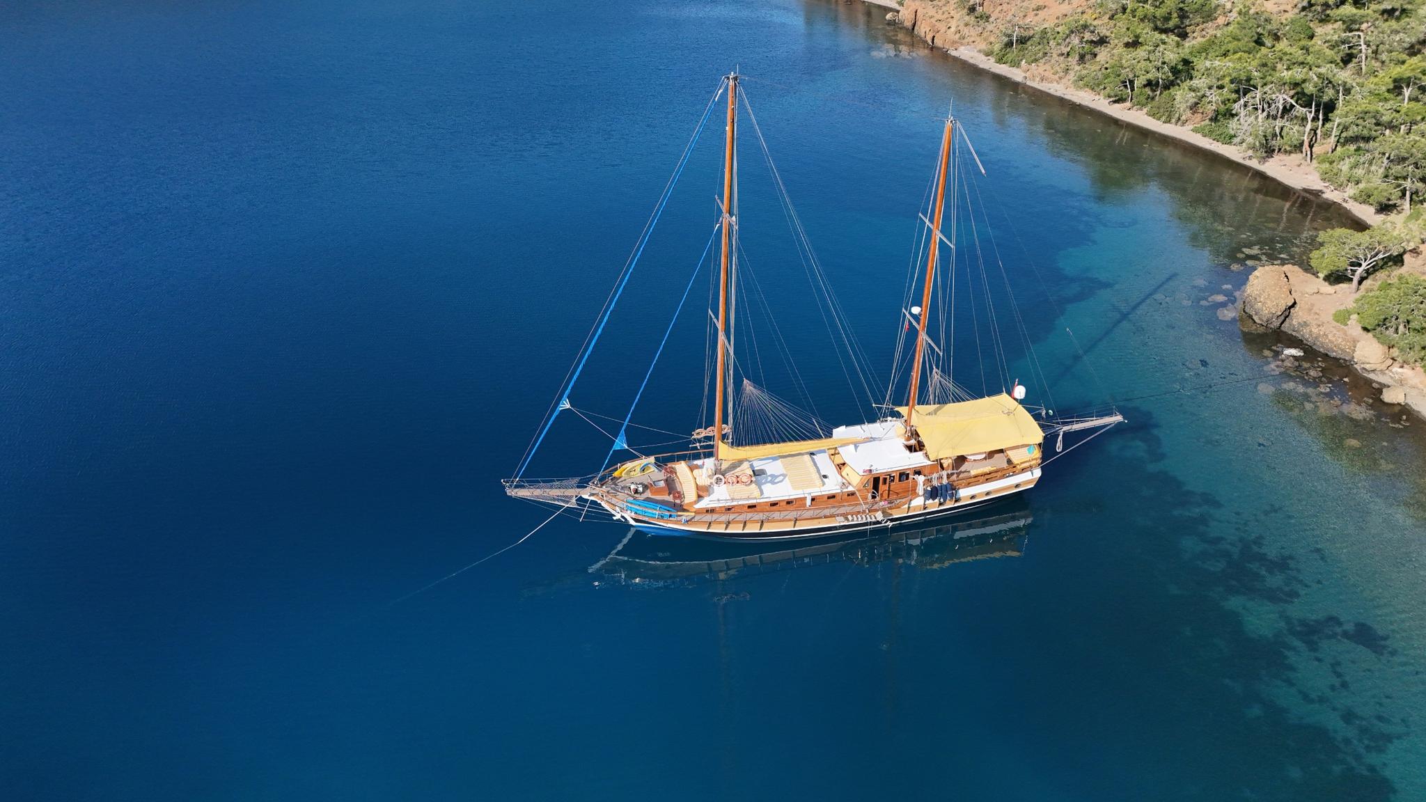 aerial view of traditional wooden gulet yacht anchored in crystal clear turquoise bay