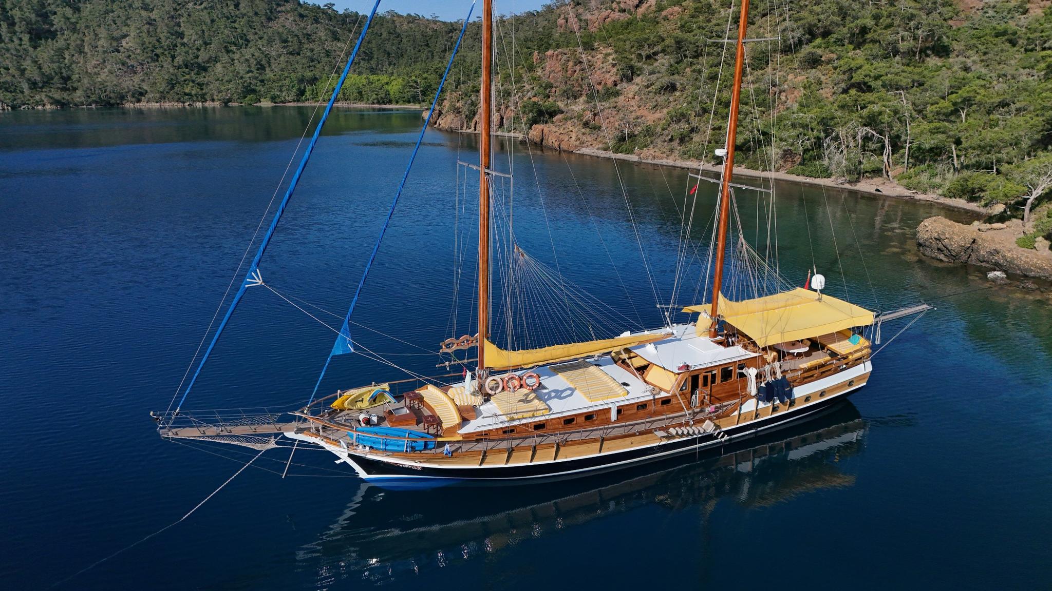 aerial view of traditional wooden gulet with two masts anchored in sheltered Mediterranean bay