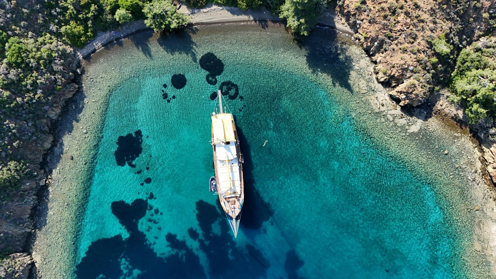 aerial view of wooden gulet yacht anchored in crystal clear turquoise Mediterranean bay