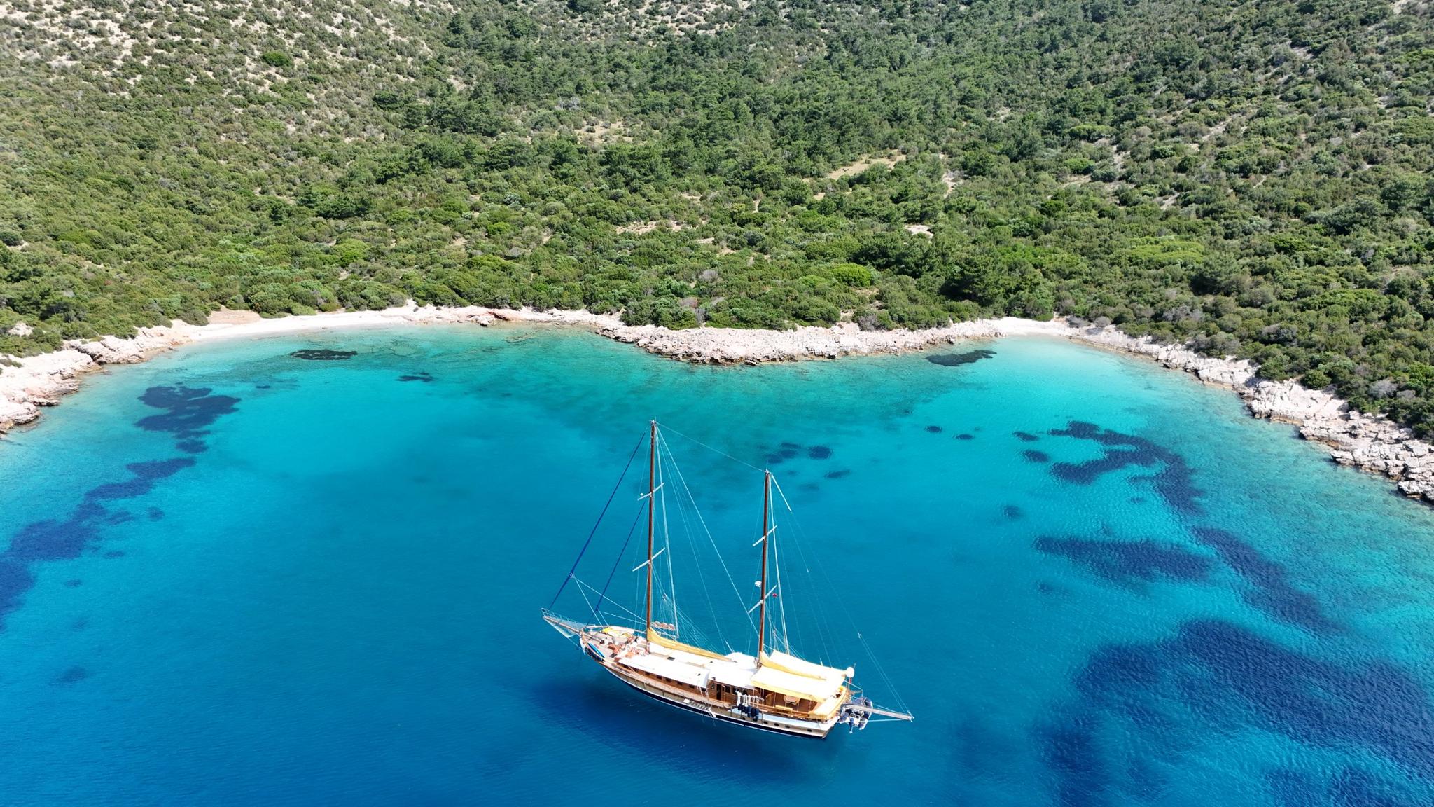 aerial view of traditional wooden gulet yacht anchored in crystal clear turquoise bay