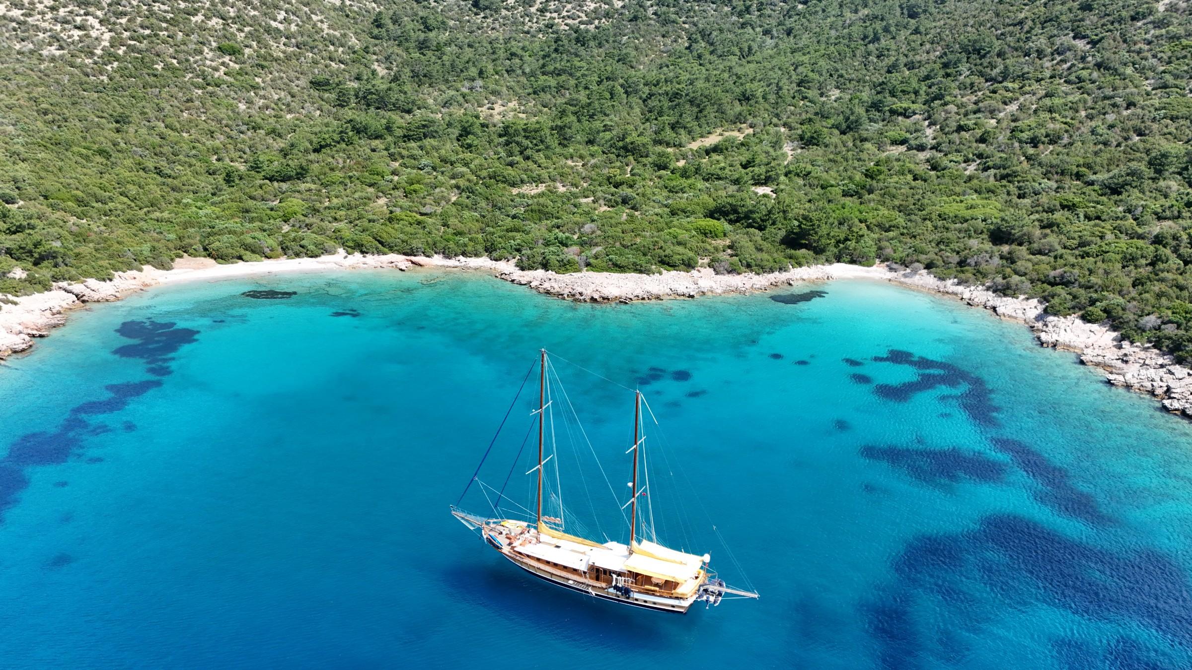 aerial view of traditional wooden gulet yacht anchored in crystal clear turquoise bay
