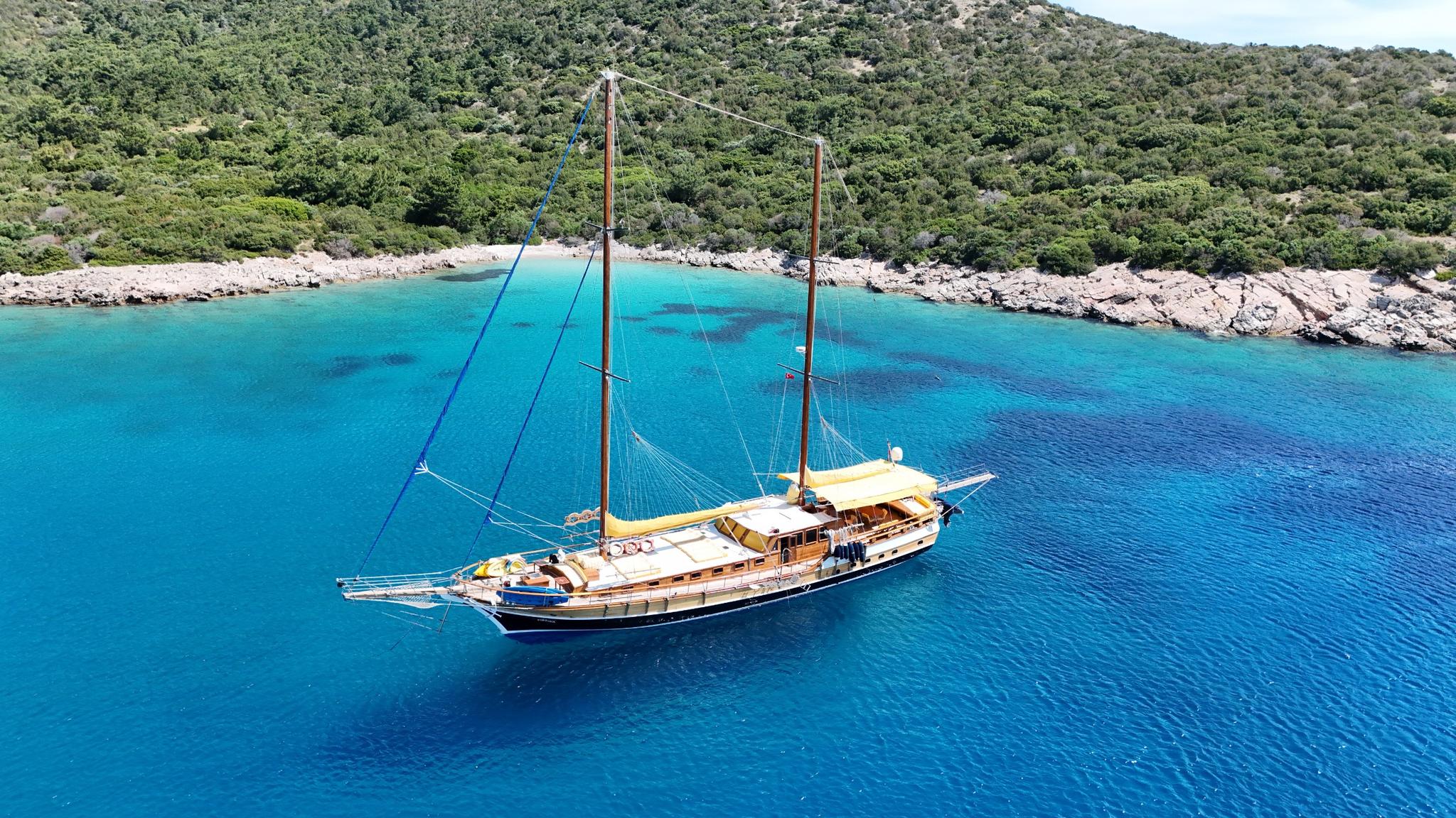 aerial view of traditional wooden gulet yacht anchored in crystal clear turquoise Mediterranean bay