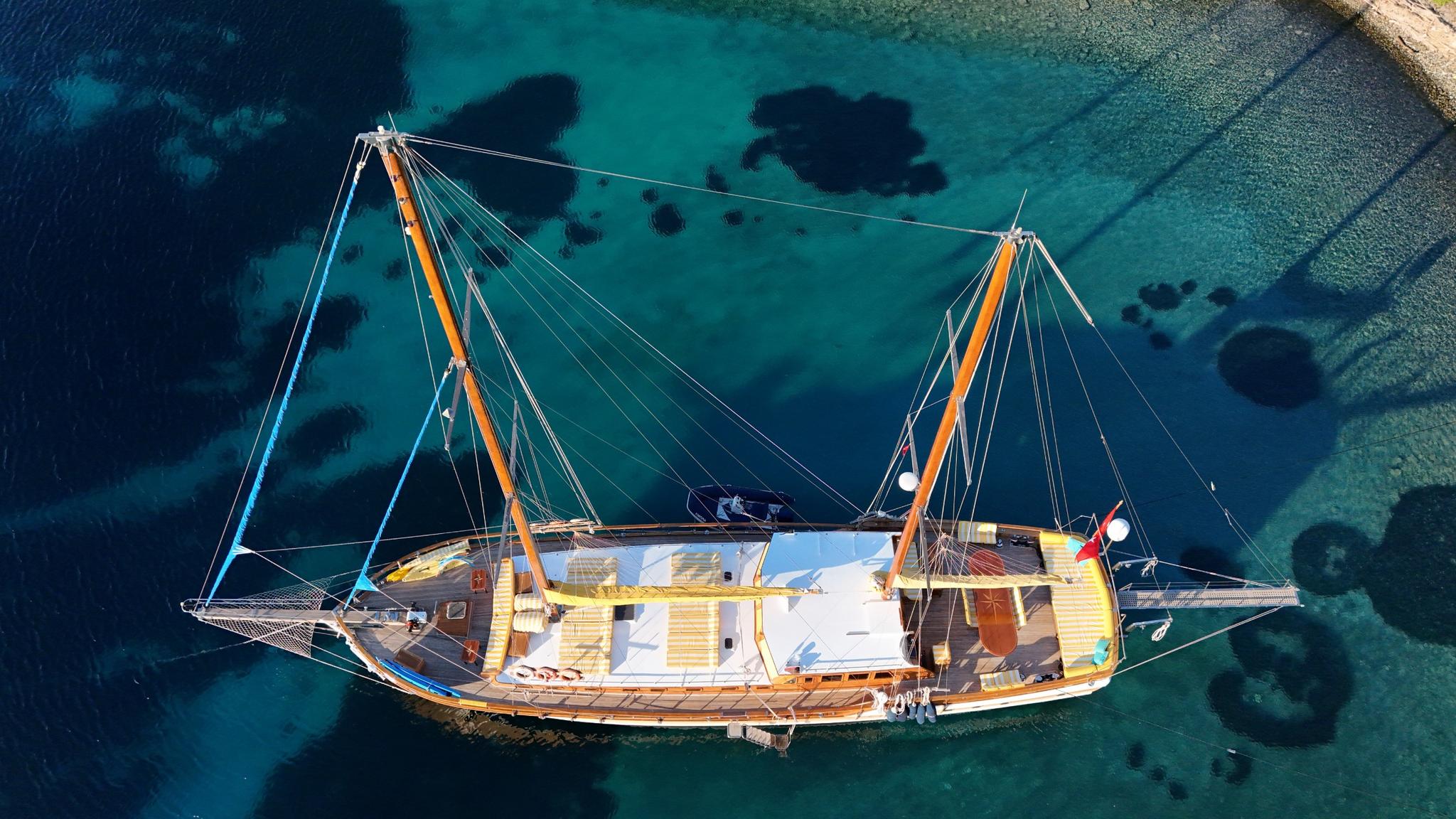 aerial view of traditional wooden gulet with two masts anchored in crystal clear turquoise Mediterranean waters