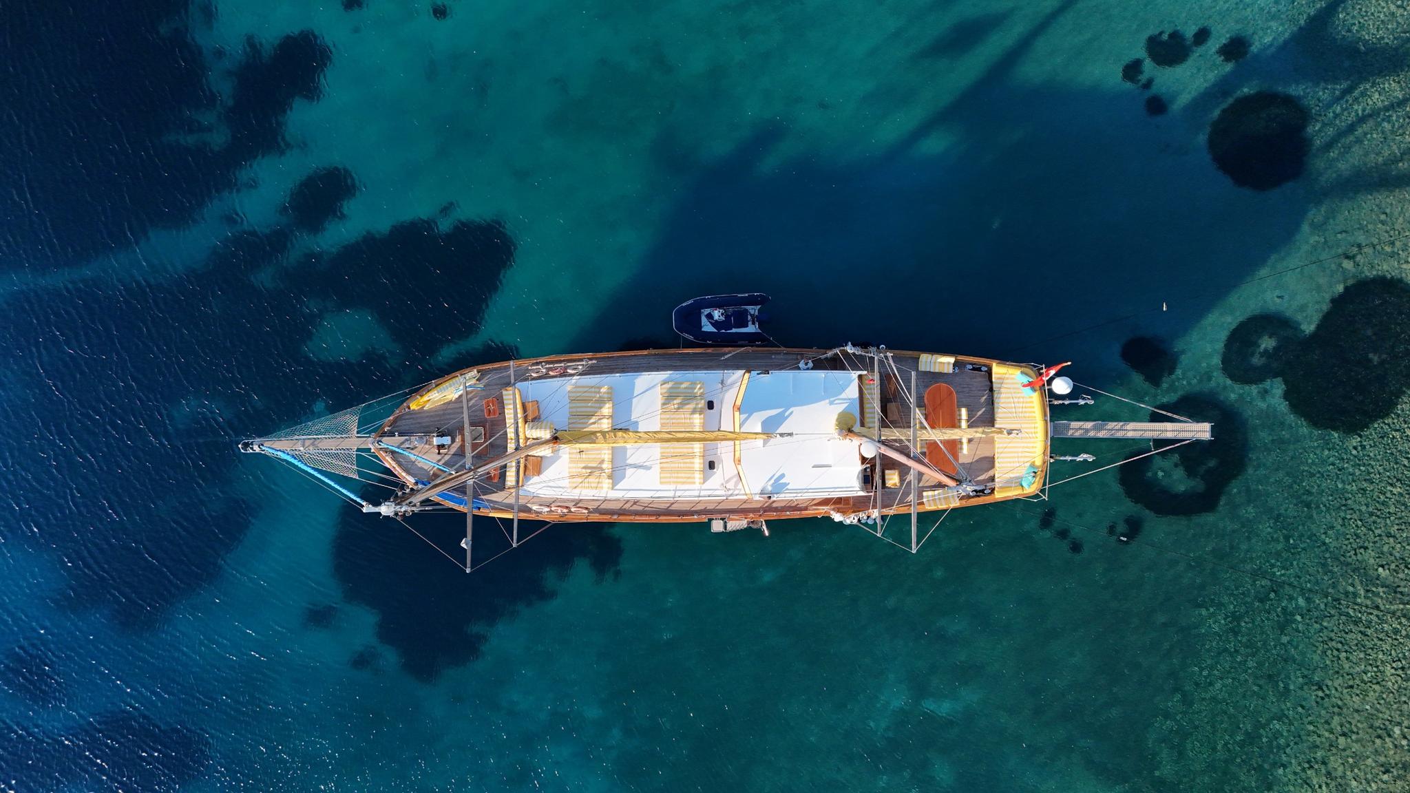 aerial view of traditional wooden gulet yacht anchored in crystal clear turquoise Mediterranean waters