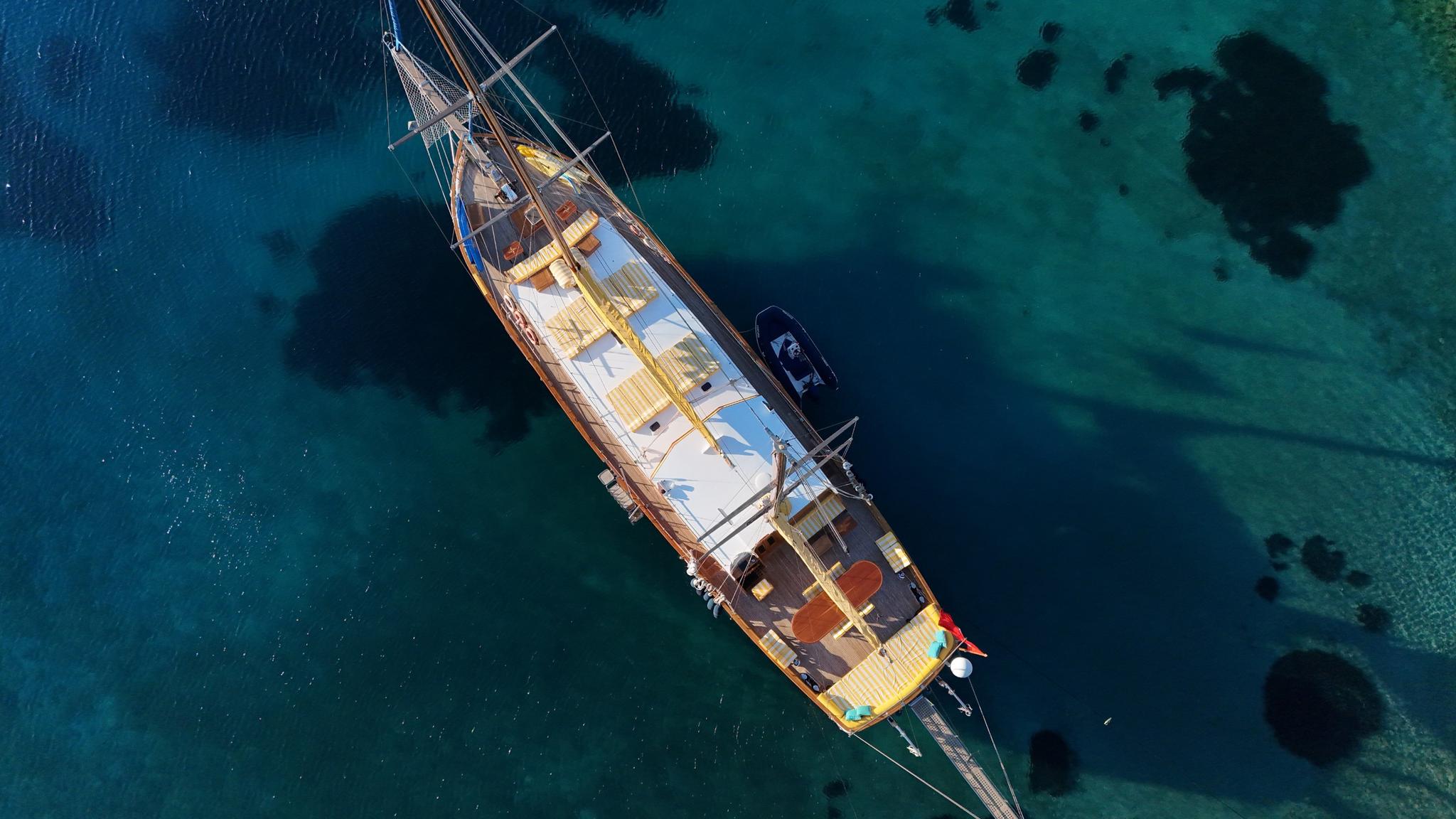 aerial view of traditional wooden gulet yacht anchored in crystal clear turquoise bay