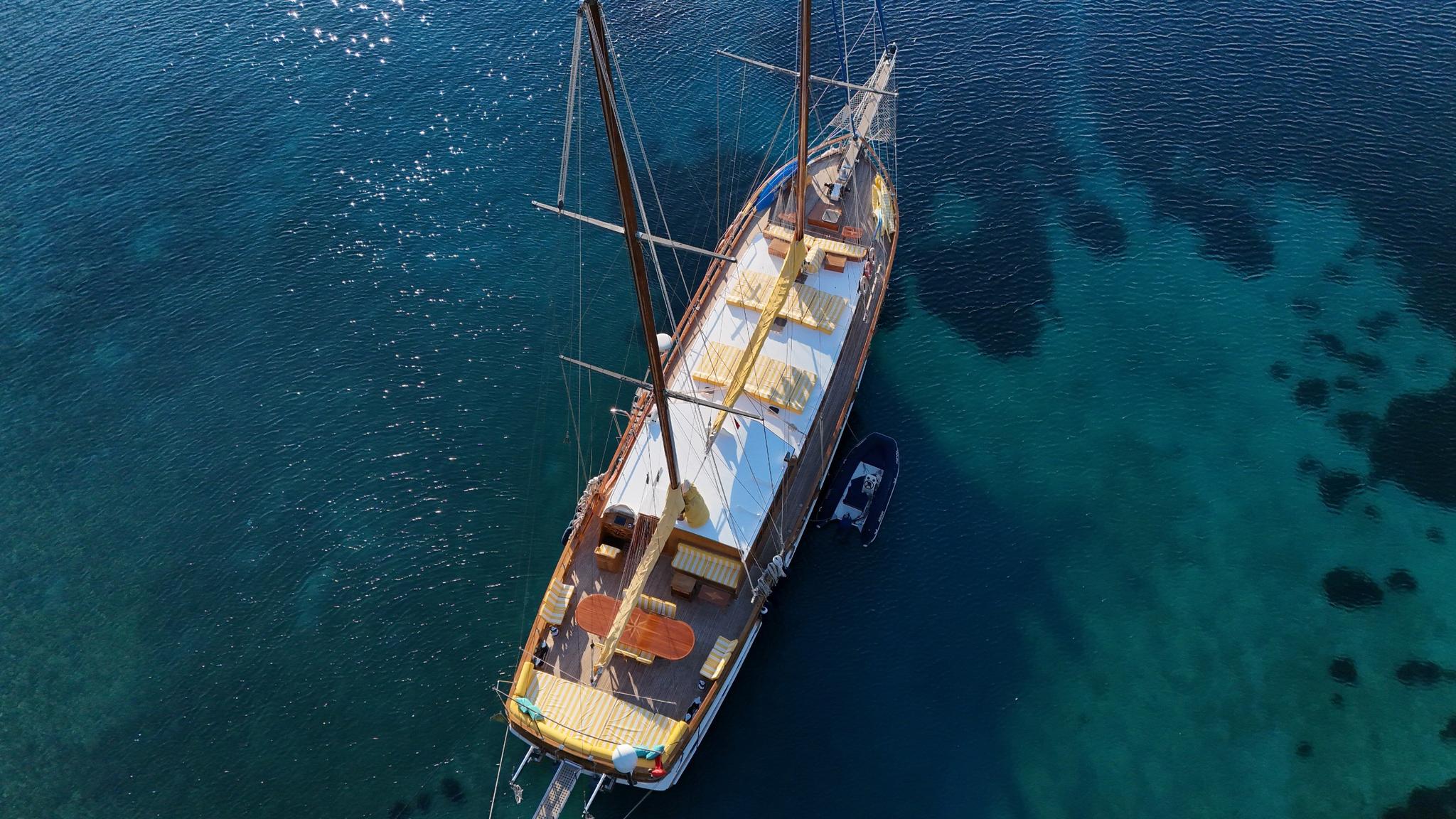 aerial drone shot of wooden gulet yacht anchored in crystal clear turquoise waters