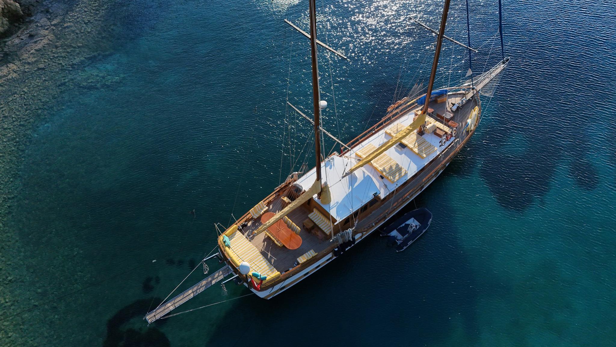 aerial view of traditional wooden gulet with two masts anchored in crystal clear turquoise waters