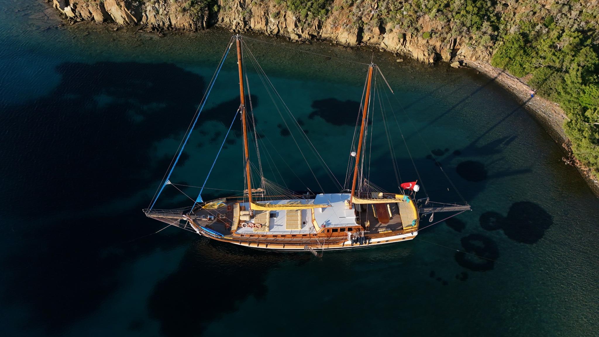 aerial view of traditional wooden gulet with two masts anchored in pristine turquoise bay