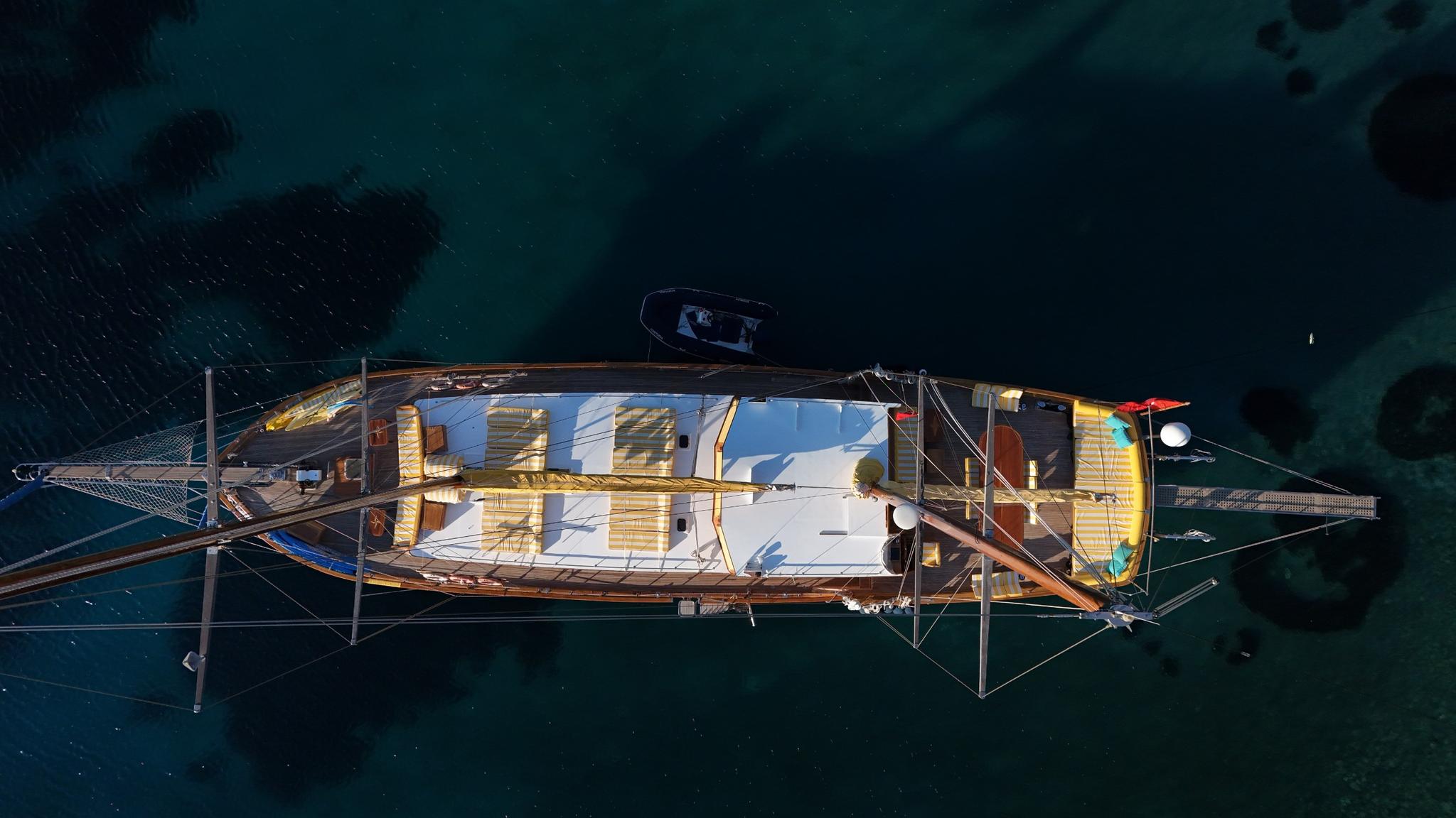 aerial drone shot of traditional wooden gulet yacht anchored in turquoise waters