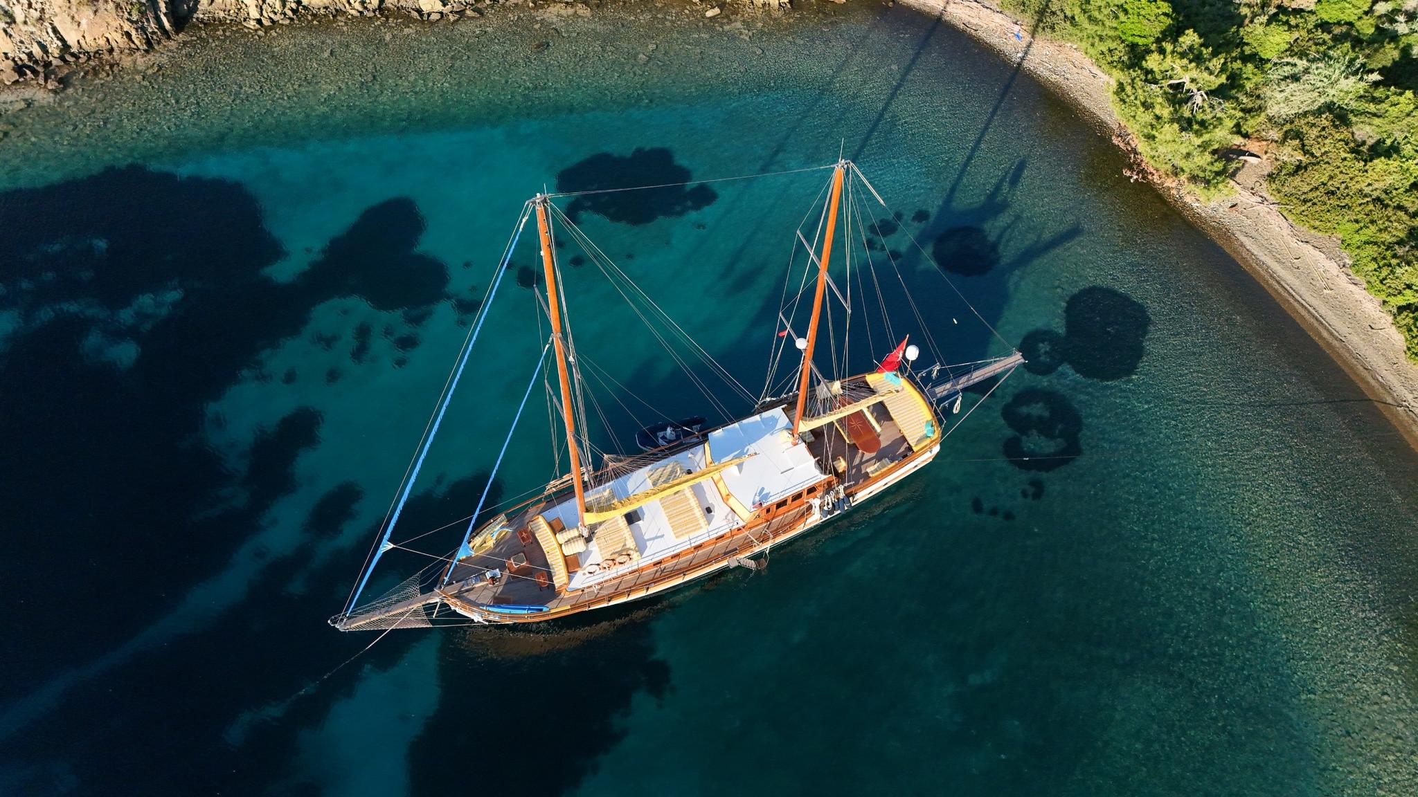 aerial view of classic wooden gulet with two masts anchored in crystal clear turquoise Mediterranean bay