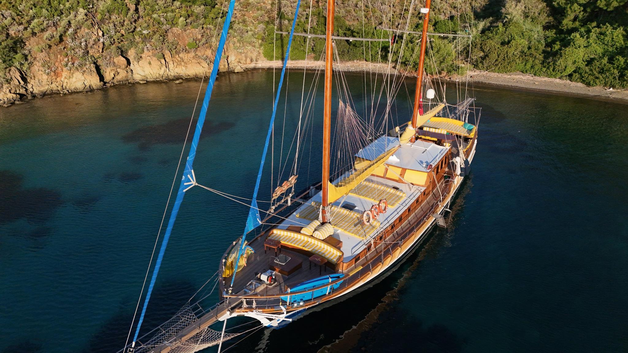 aerial view of traditional wooden gulet with two masts anchored in protected turquoise bay