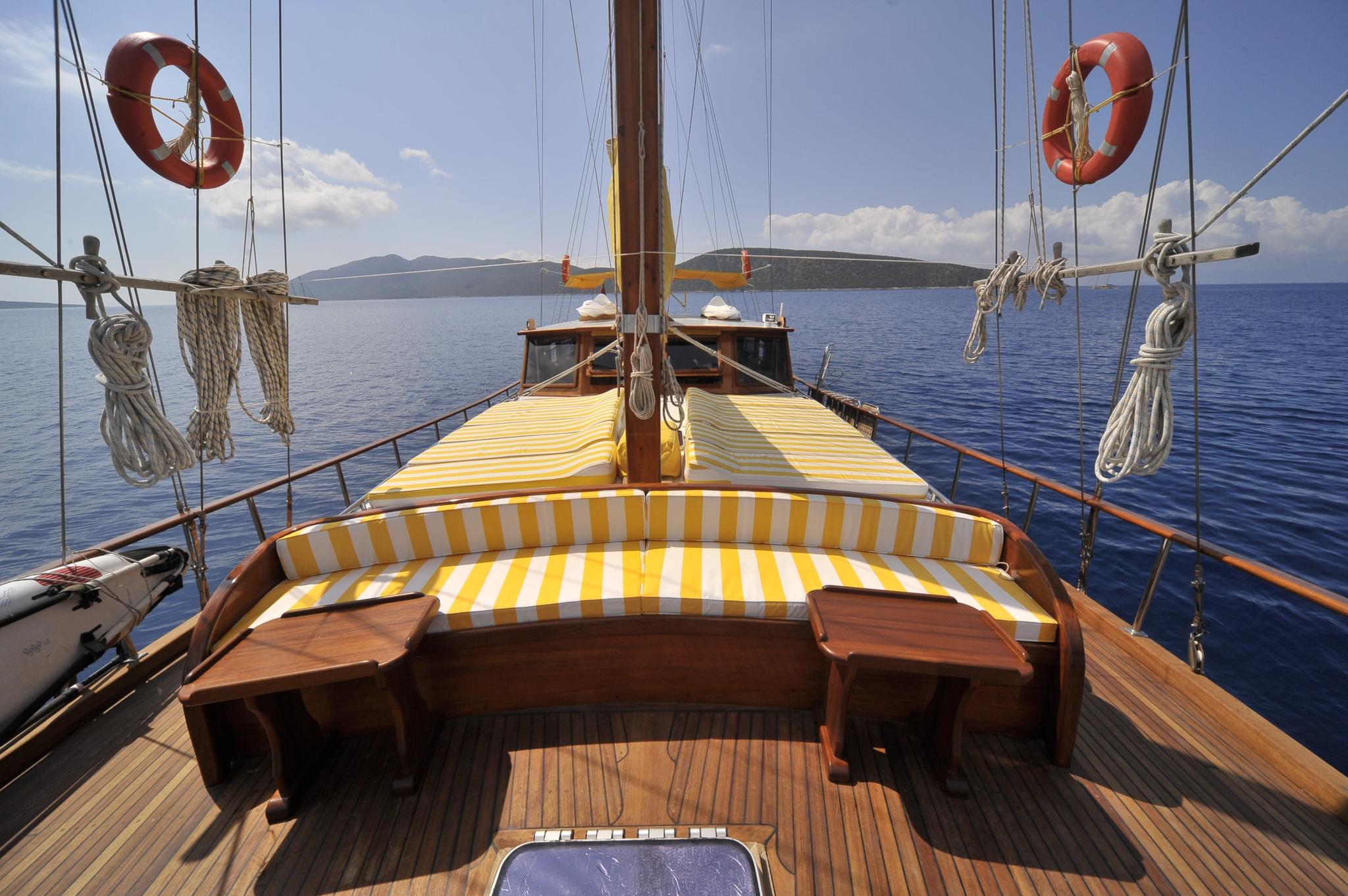 gulet bow seating area with yellow and white striped cushions overlooking blue Mediterranean waters