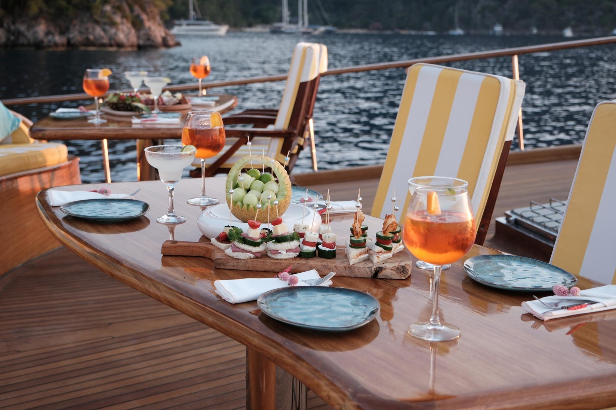 yacht dining table with appetizer platters, cocktails and wine glasses during sunset