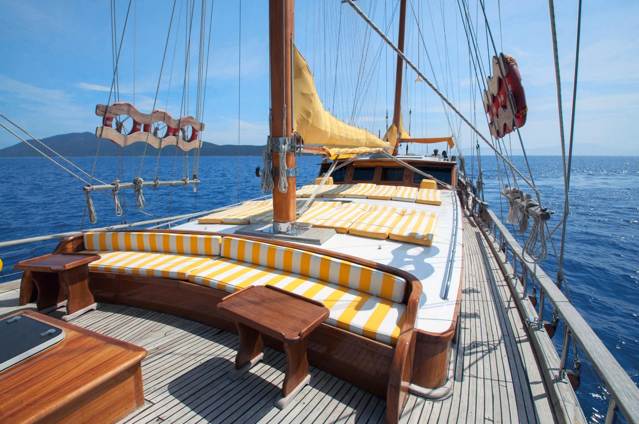 gulet forward deck with built-in seating featuring yellow and white striped cushions