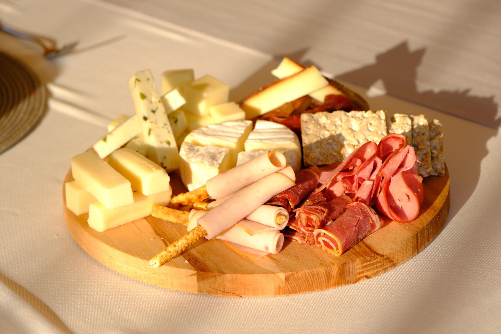wooden charcuterie board with assorted cheeses, cured meats and crackers on yacht deck