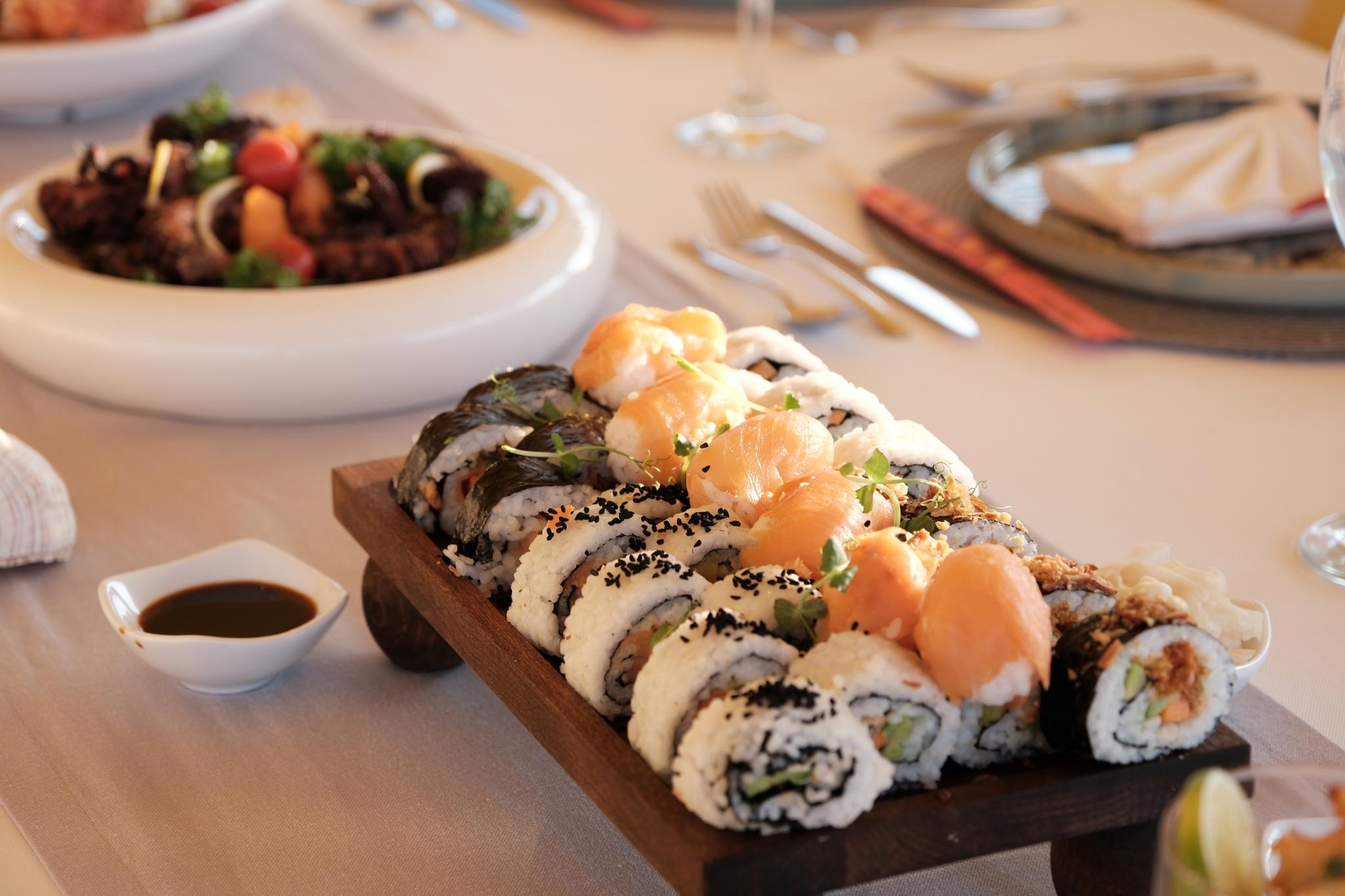 sushi platter with salmon rolls and black sesame seeds served with salad on yacht dining table