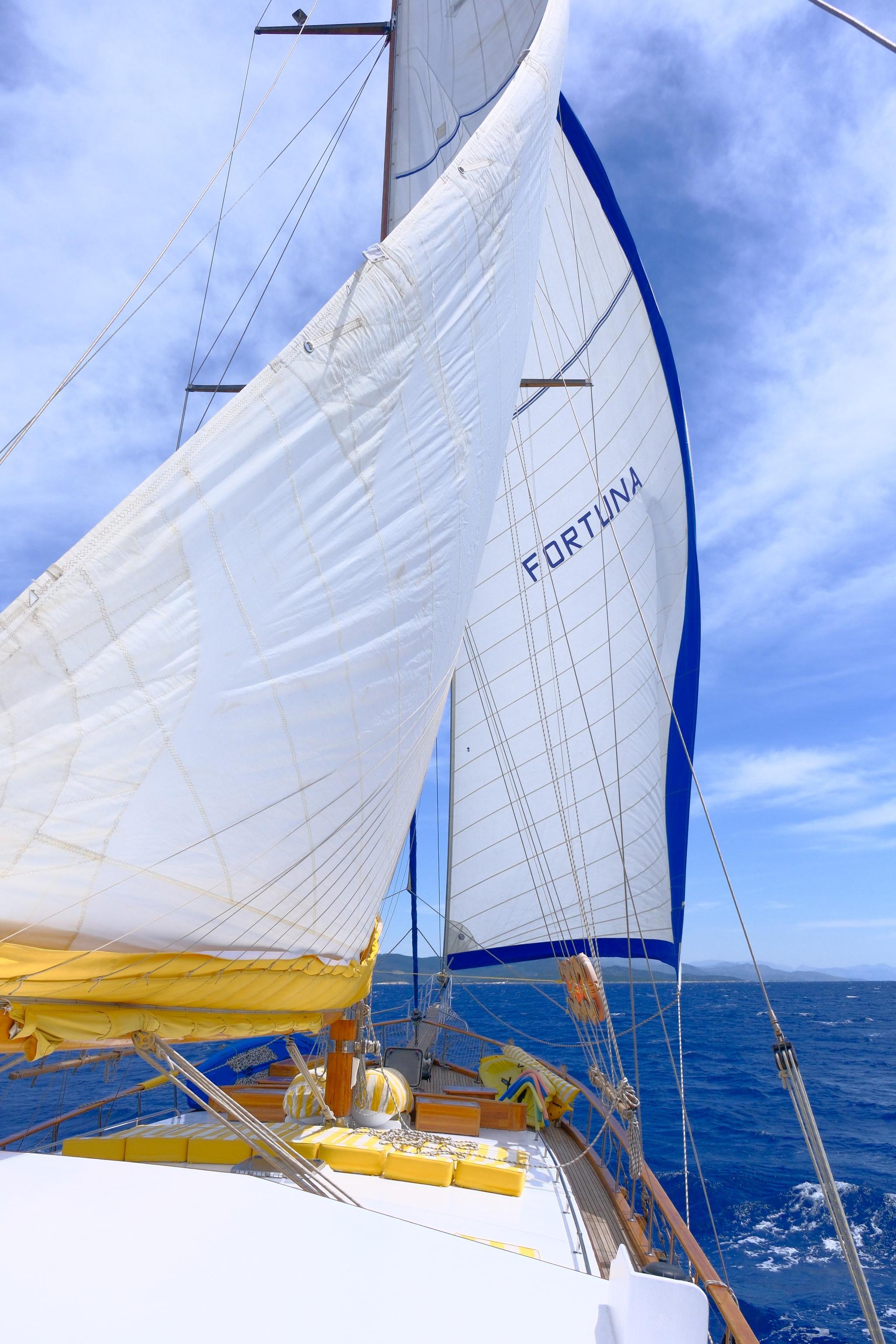 sailing gulet Fortuna with white mainsail and jib deployed on blue Mediterranean waters